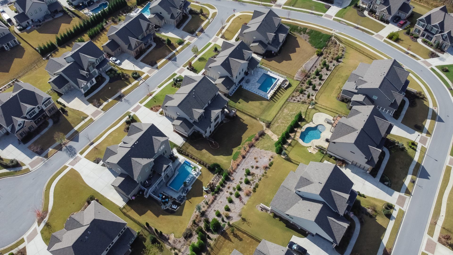 Aerial view of a suburban neighborhood with modern houses, winding streets, and landscaped yards