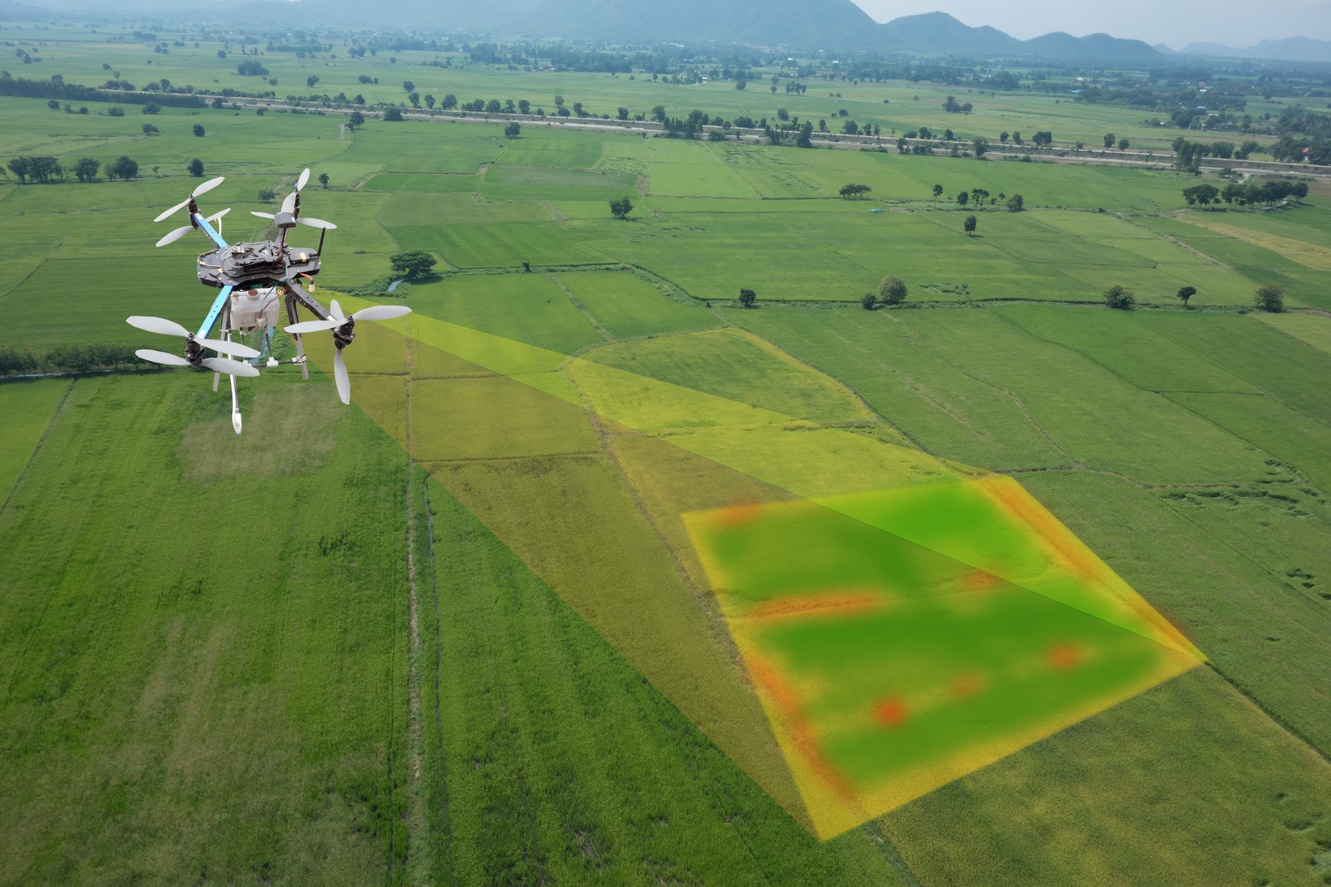 Drone spraying crop field with yellow-green treatment zone over lush farmland