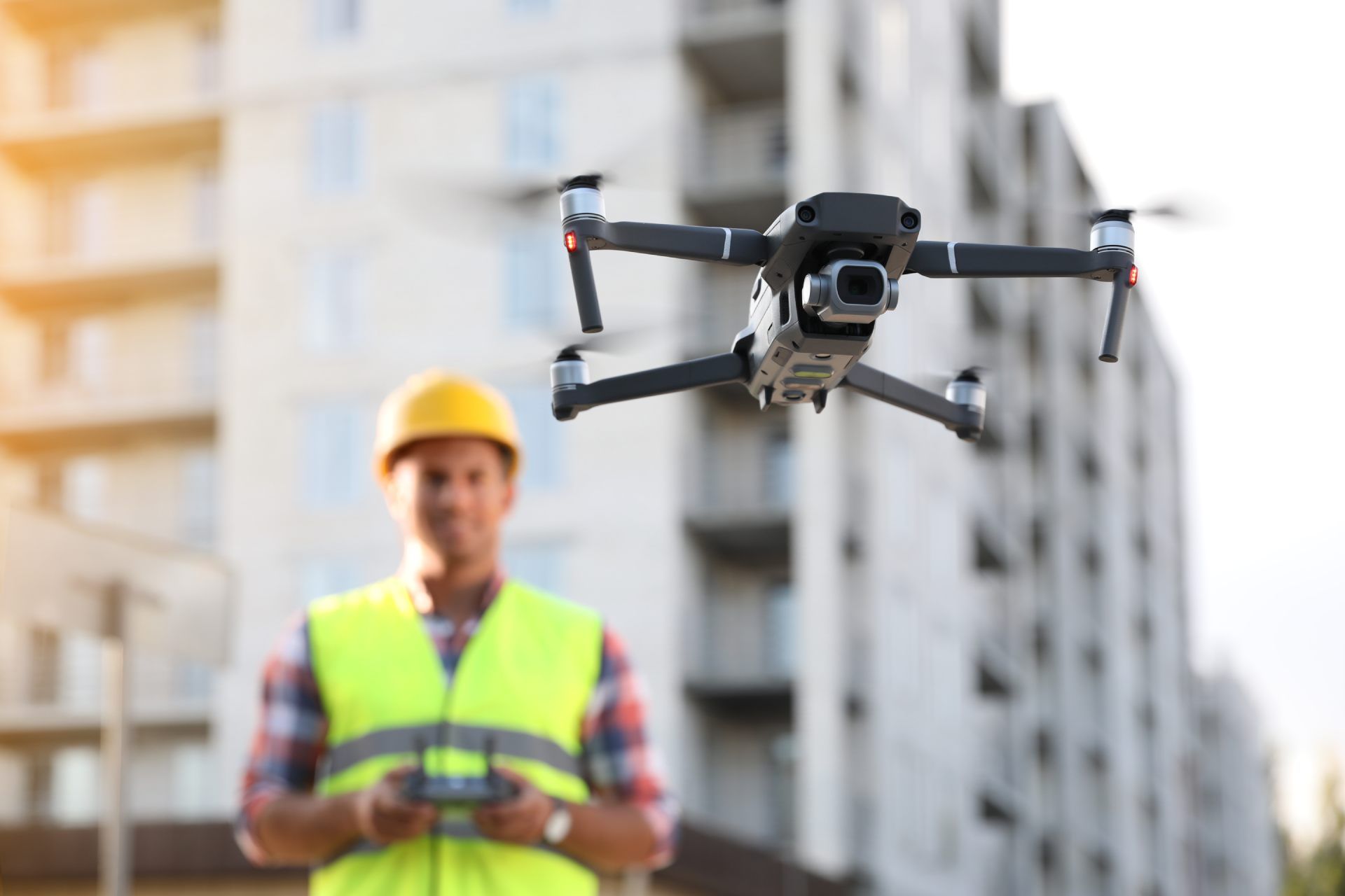 Workers in safety gear on a construction site, with a drone flying overhead. Text reads 