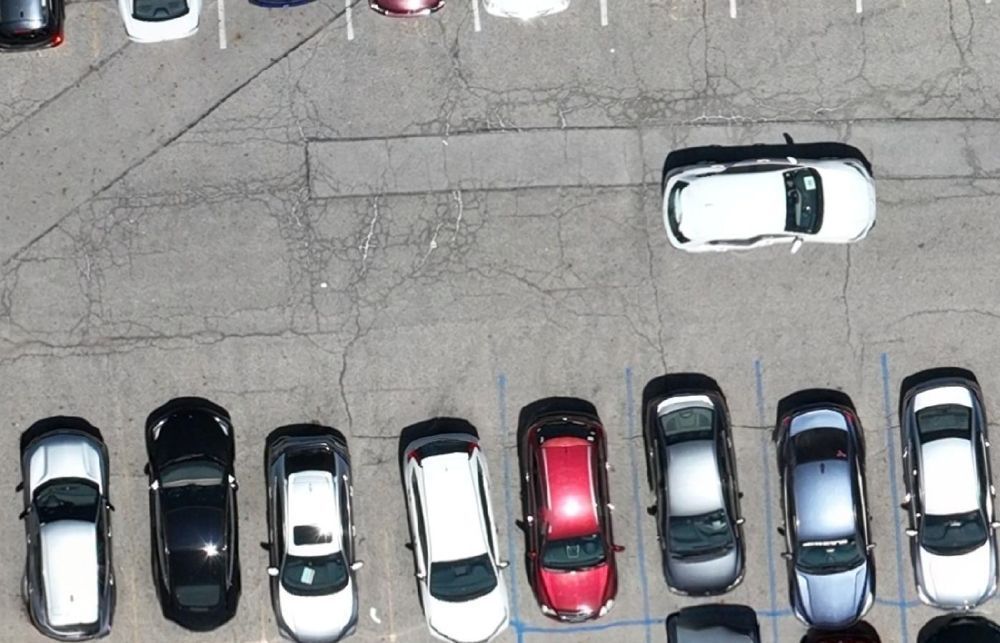 Close-up taken from the same drone map showing individual parked cars, painted stall lines and fine cracking in the asphalt