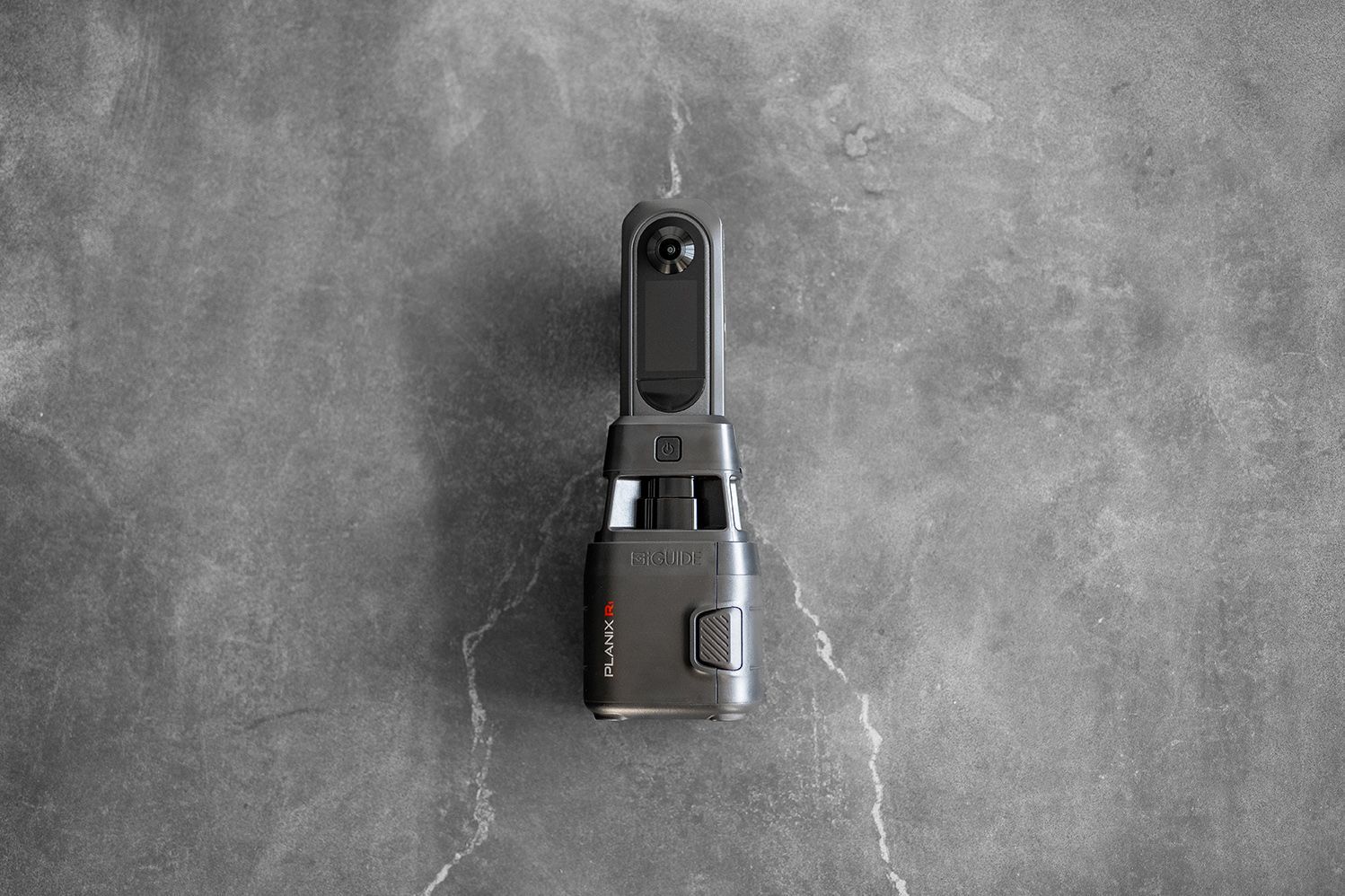 Black handheld device with a rectangular body on a gray textured surface.
