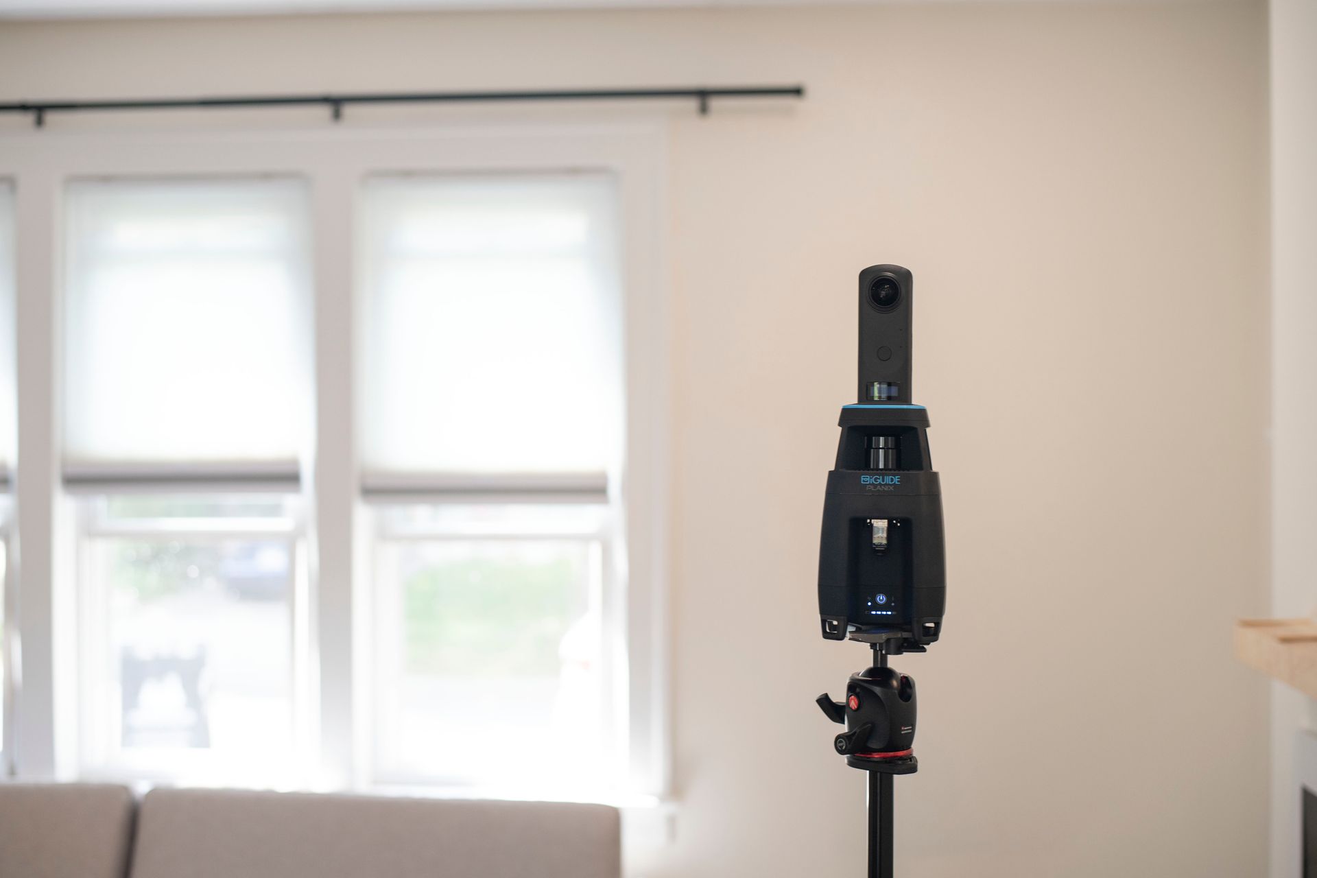 Black 360 camera on a tripod in a bright room with windows