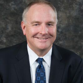A man in a suit and tie is smiling for the camera.