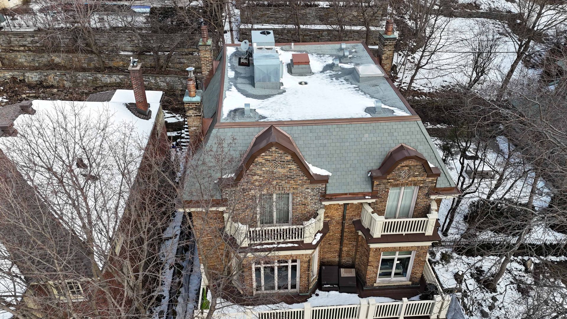 Vue aérienne d'une maison en briques enneigée avec un toit plat et des maisons voisines dans un quartier en hiver
