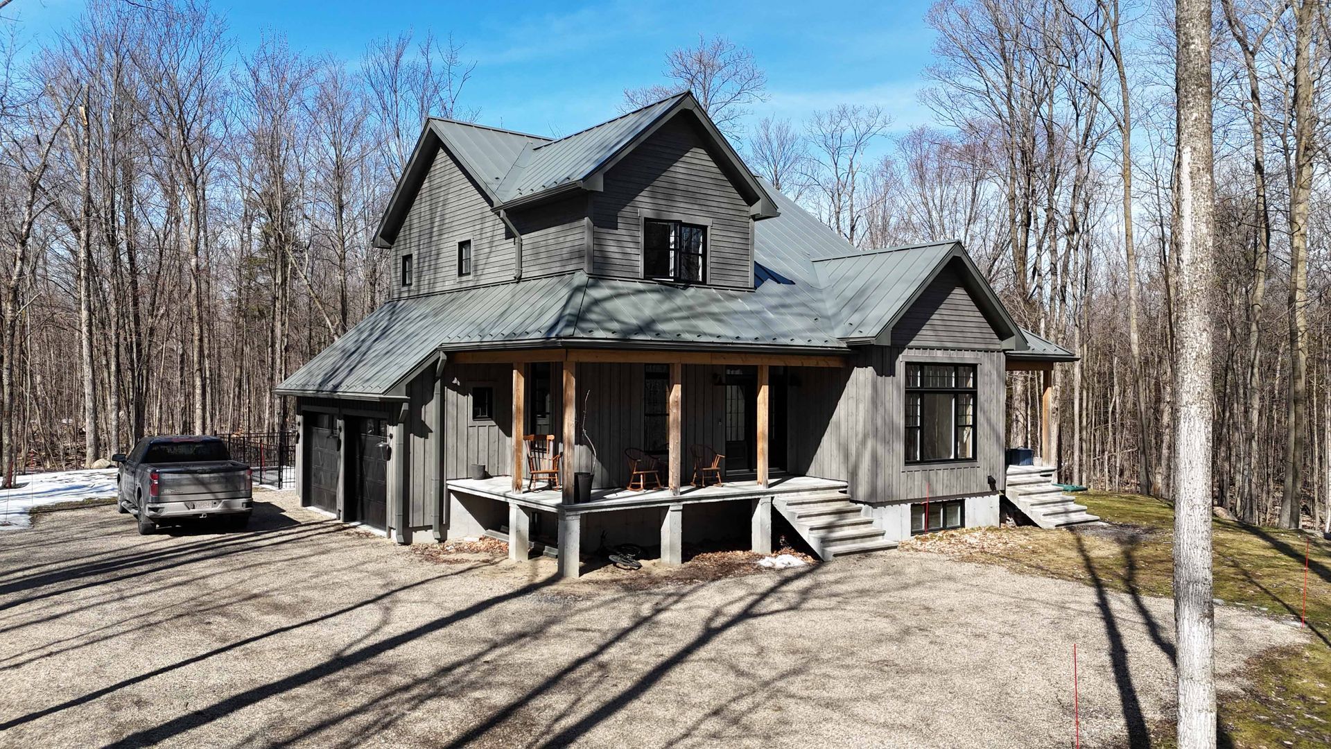 Cabane grise rustique avec véranda couverte dans une zone boisée sans feuilles par une journée ensoleillée