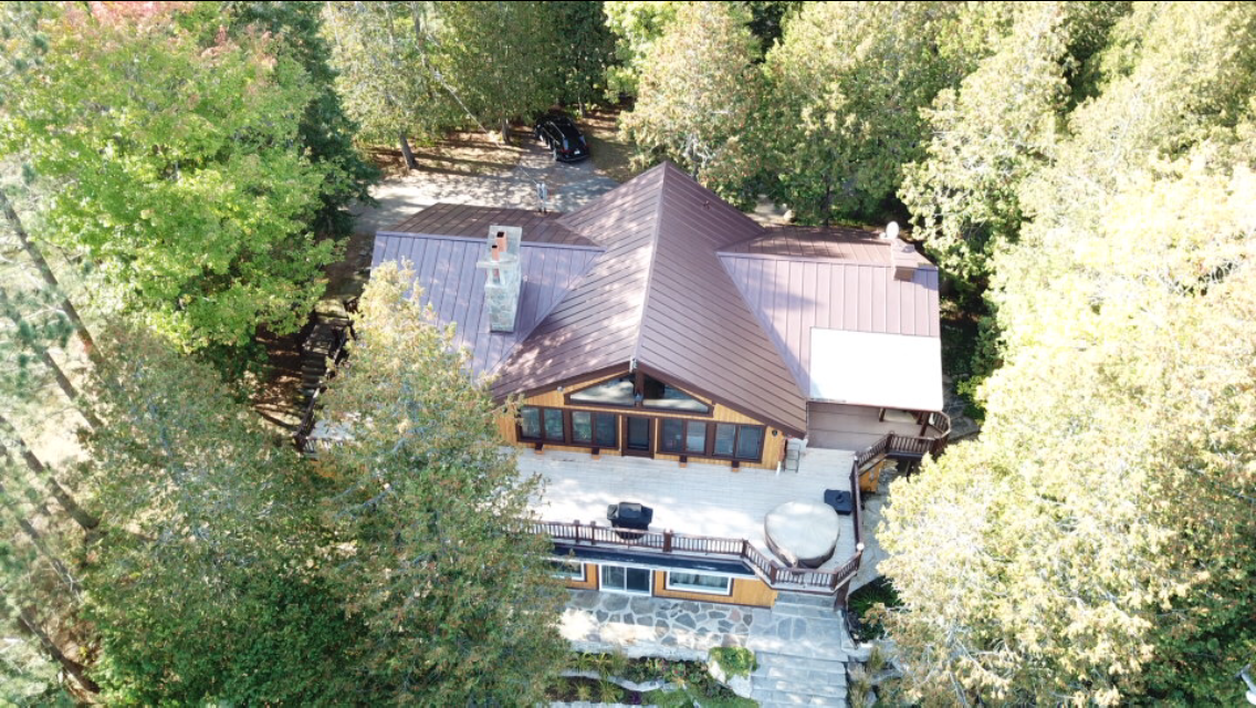 Une vue aérienne d'une maison au milieu d'une forêt entourée d'arbres.