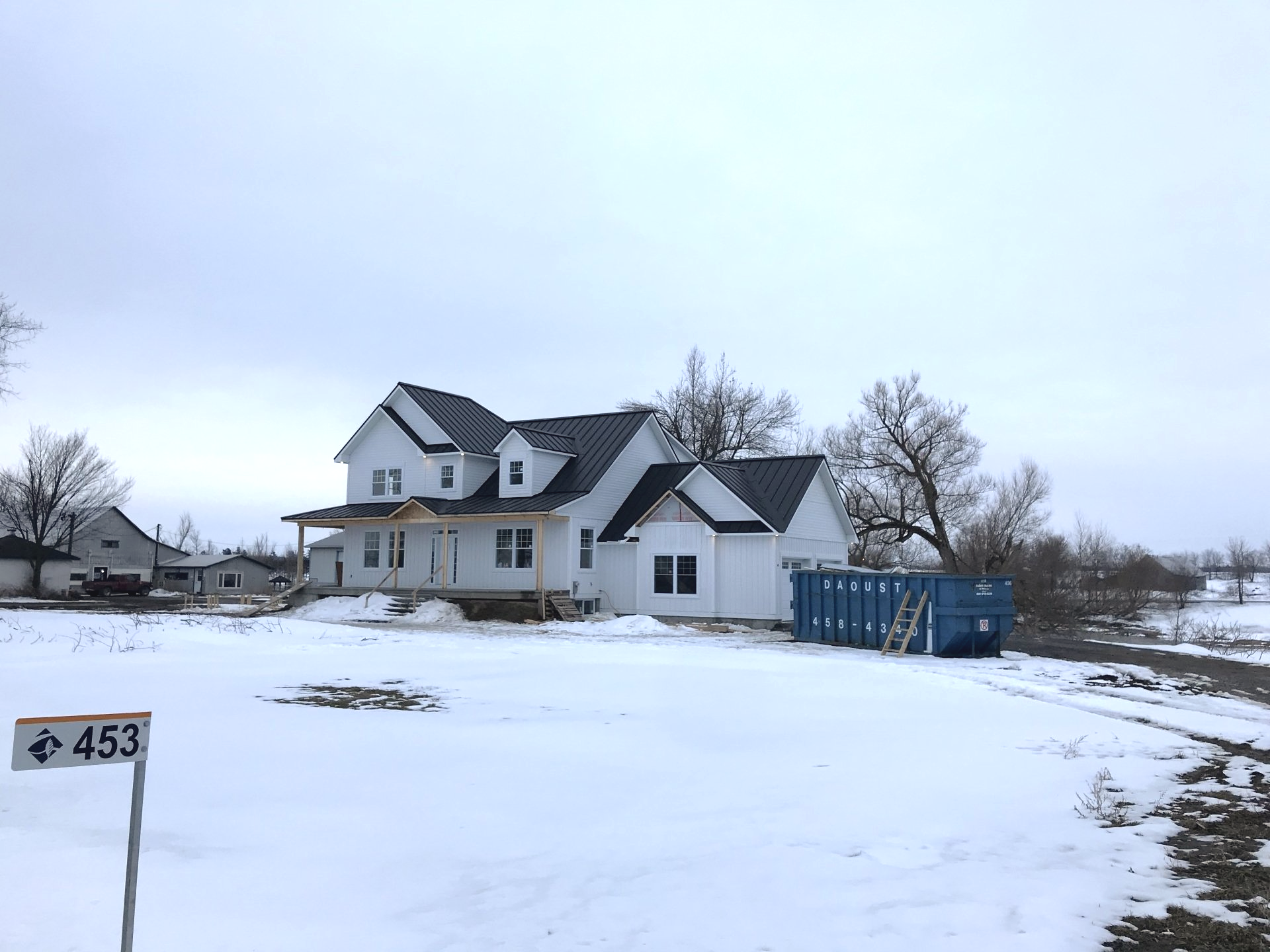 Une grande maison blanche se trouve au milieu d'un champ couvert de neige.