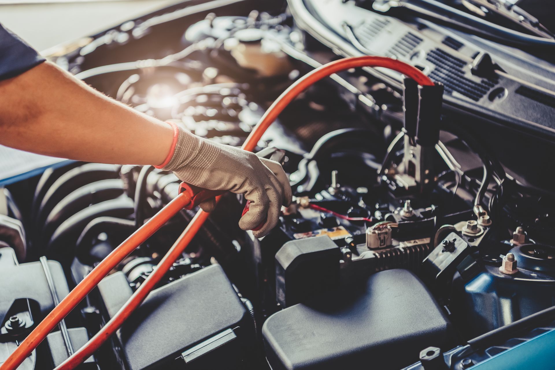 Close-up of a mechanic jump-starting a car battery with red jumper cables. Close-up of a mechanic jump-starting a car battery with red jumper cables.