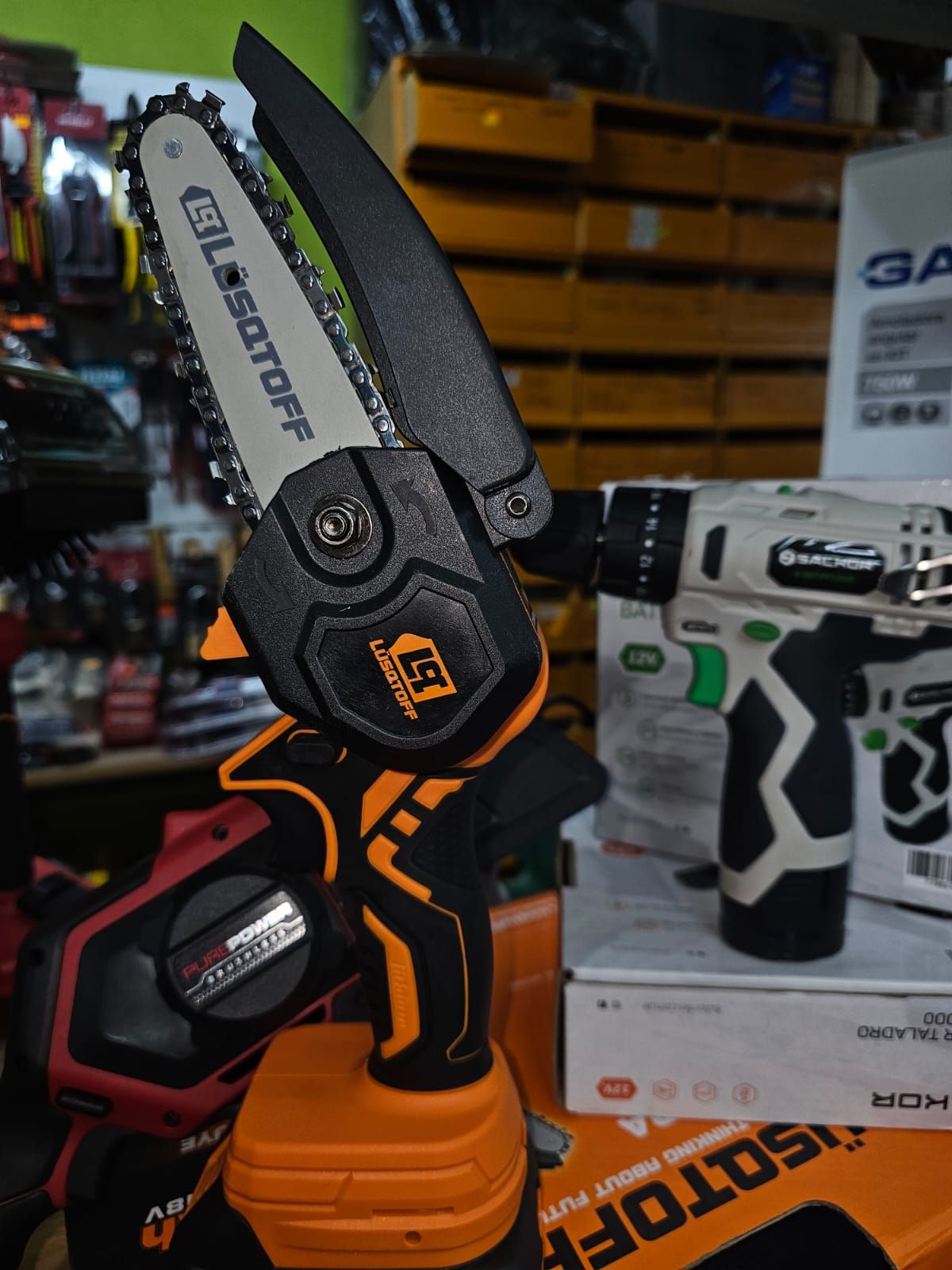 Una motosierra está junto a un taladro en una tienda.