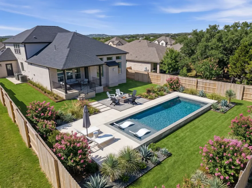 custom pool construction services in Austin, TX. 12x28 swimming pool with tanning ledge and lounge chairs.