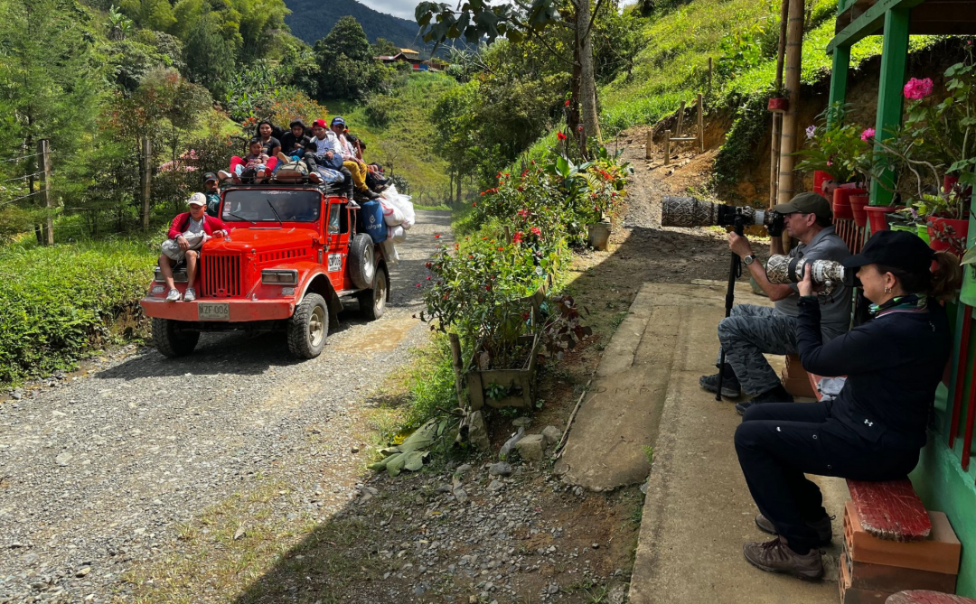 Red off-road jeep carrying passengers on a gravel mountain road. 