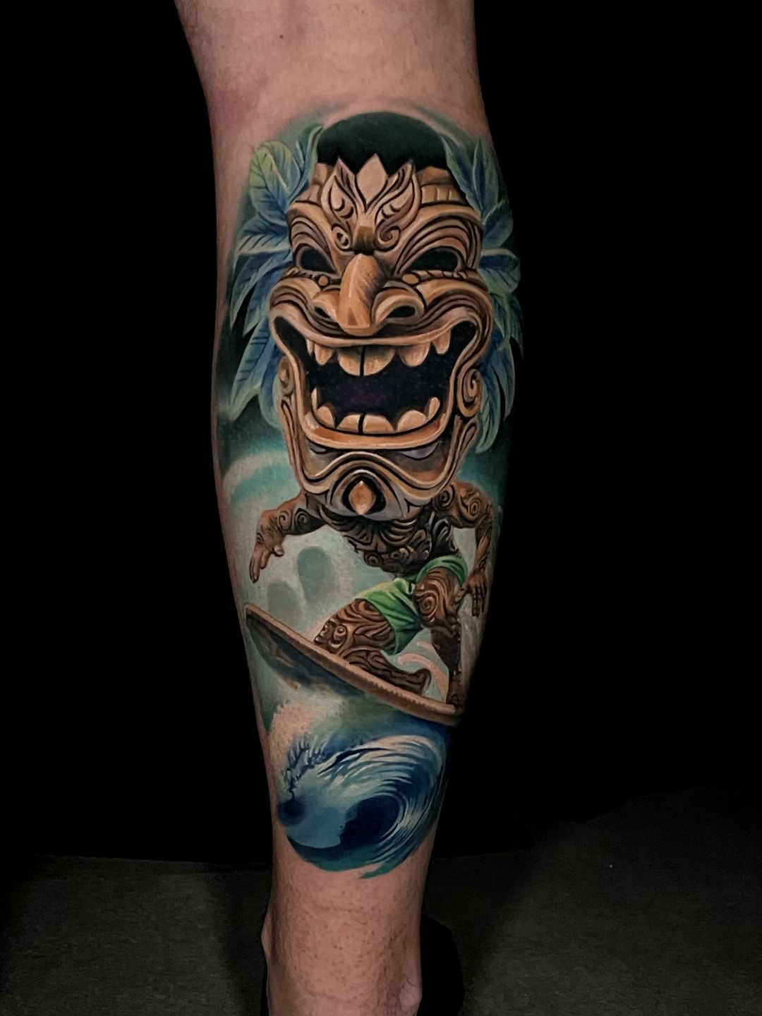 A person has a tattoo of a tiki on their leg.