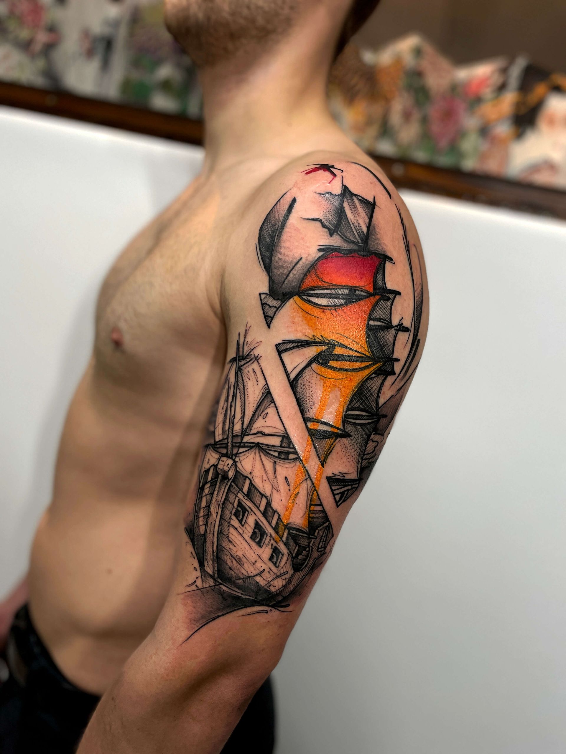 Mann mit einem bunten, abstrakten Tattoo eines Schiffs auf seinem Oberarm.