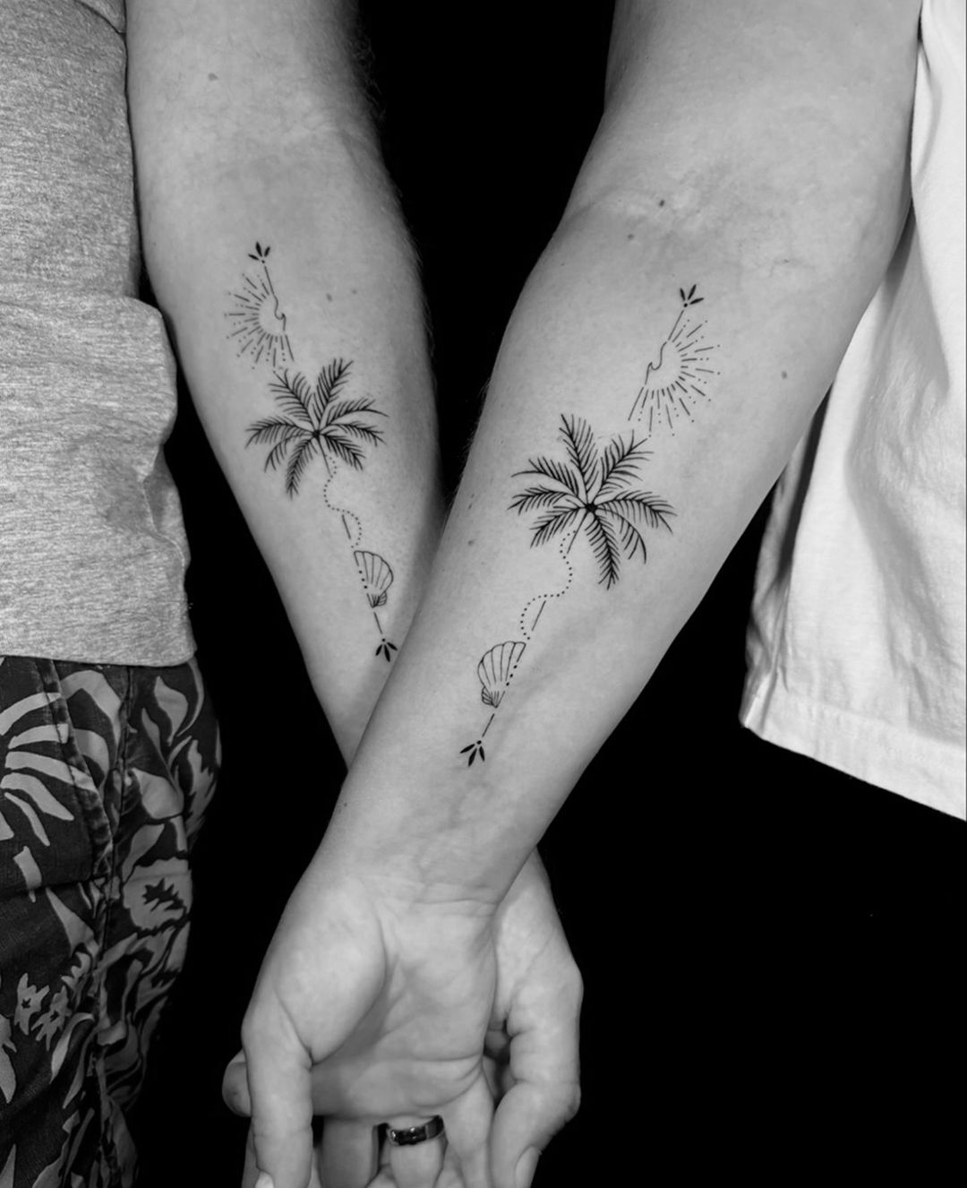 Schwarz-weißes Blumentattoo auf dem Arm einer Person, neben einem Button-Down-Hemd.