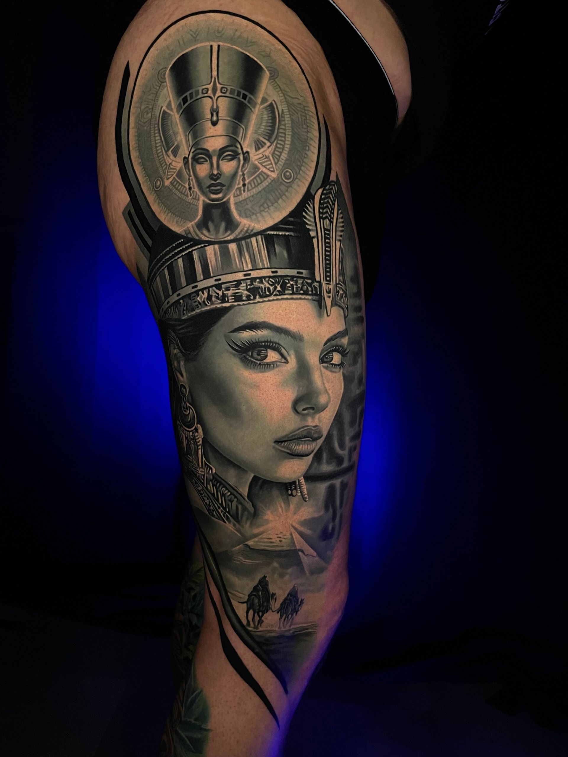 Schwarzes und graues Tattoo einer Frau mit einer verzierten Krone auf einem Arm.