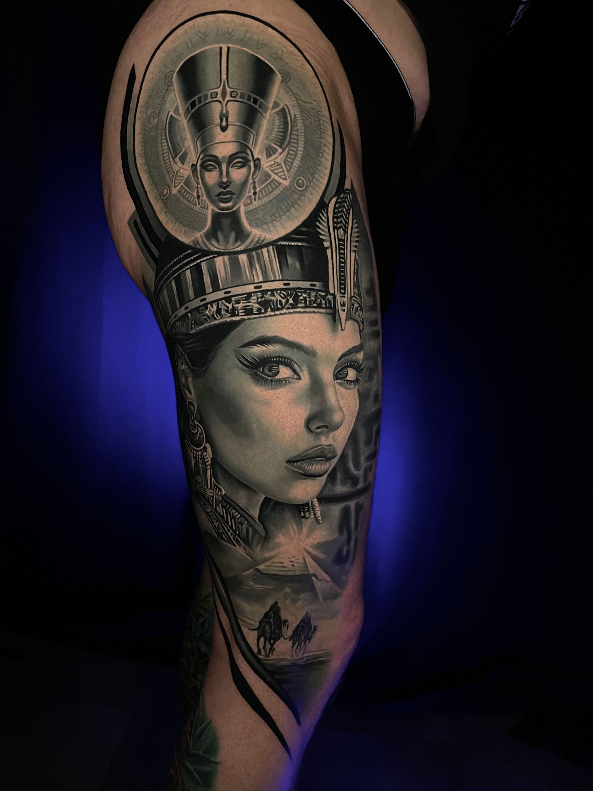 Schwarzes und graues Tattoo einer Frau mit ägyptischem Kopfschmuck auf einem Bein.