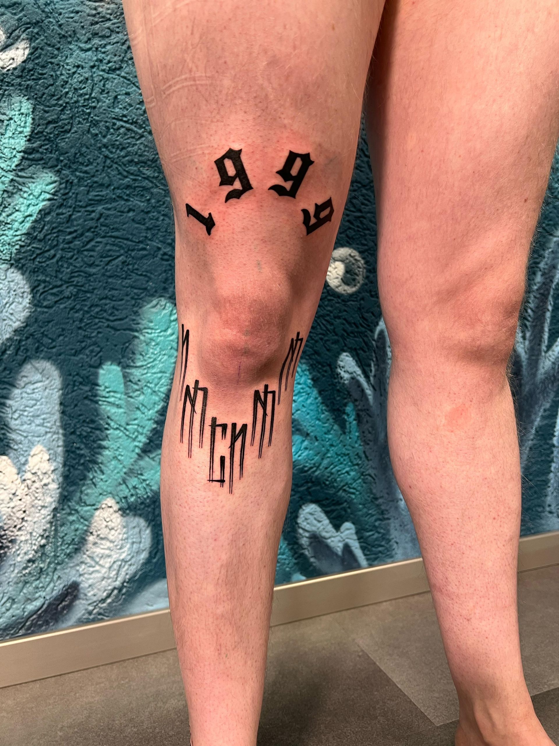 A person has a tattoo on their knee that says 1999.