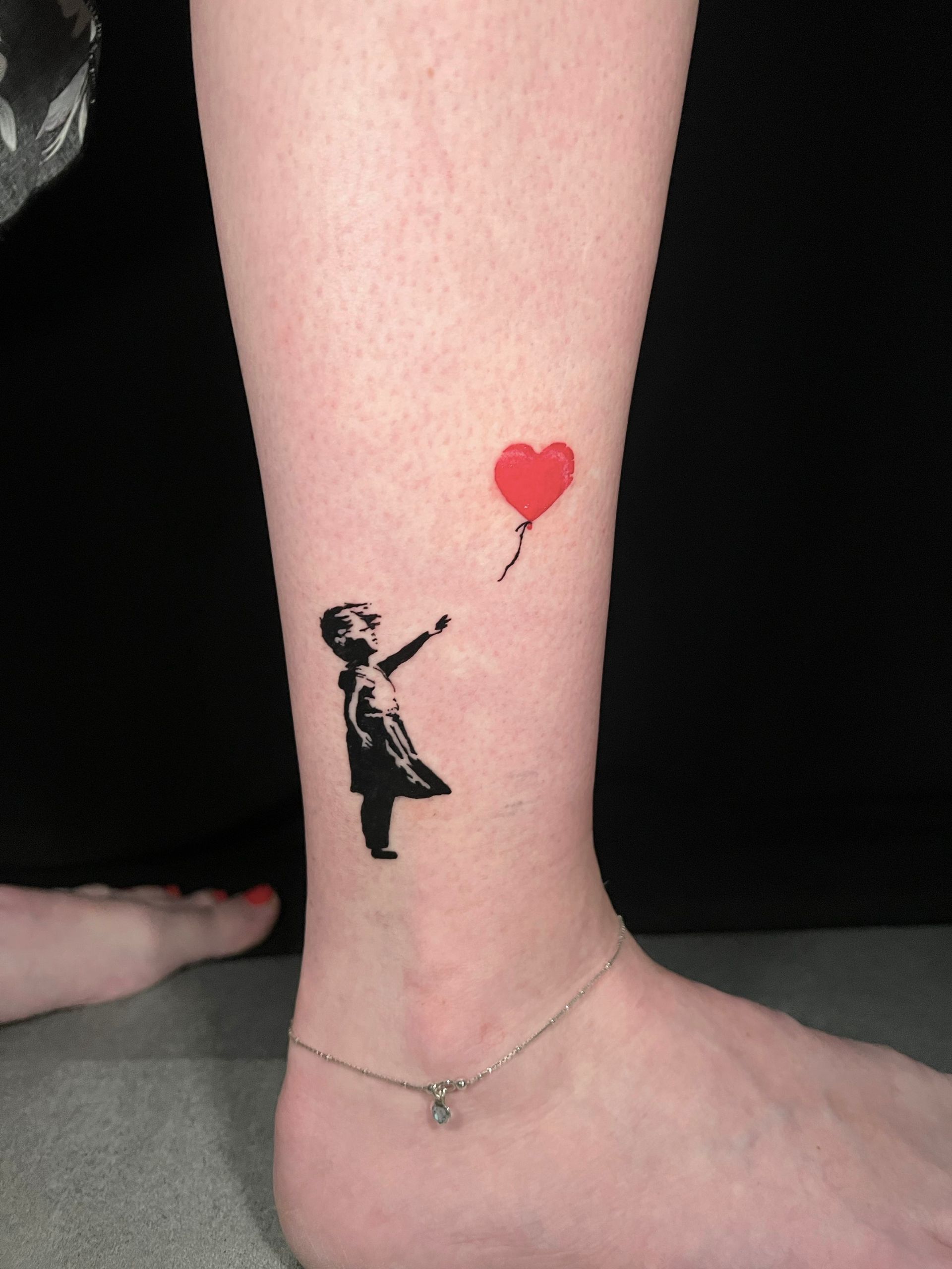 A tattoo of a girl holding a red heart shaped balloon