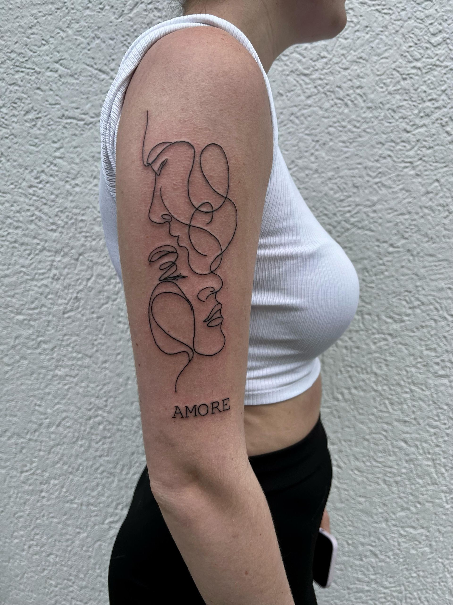 A woman has a tattoo on her arm that says amore.