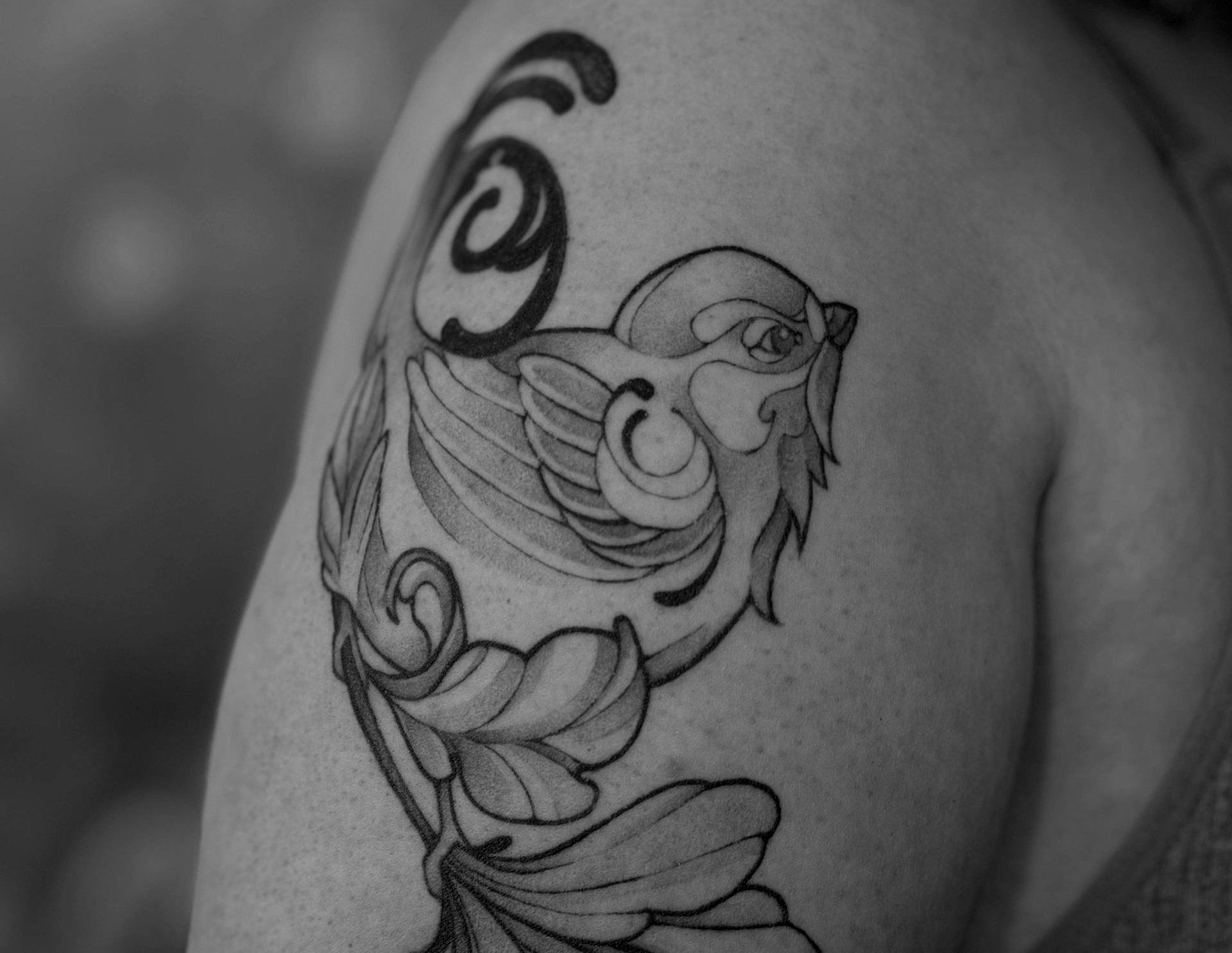 Schwarz-weißes Blumentattoo auf dem Arm einer Person, neben einem Button-Down-Hemd.