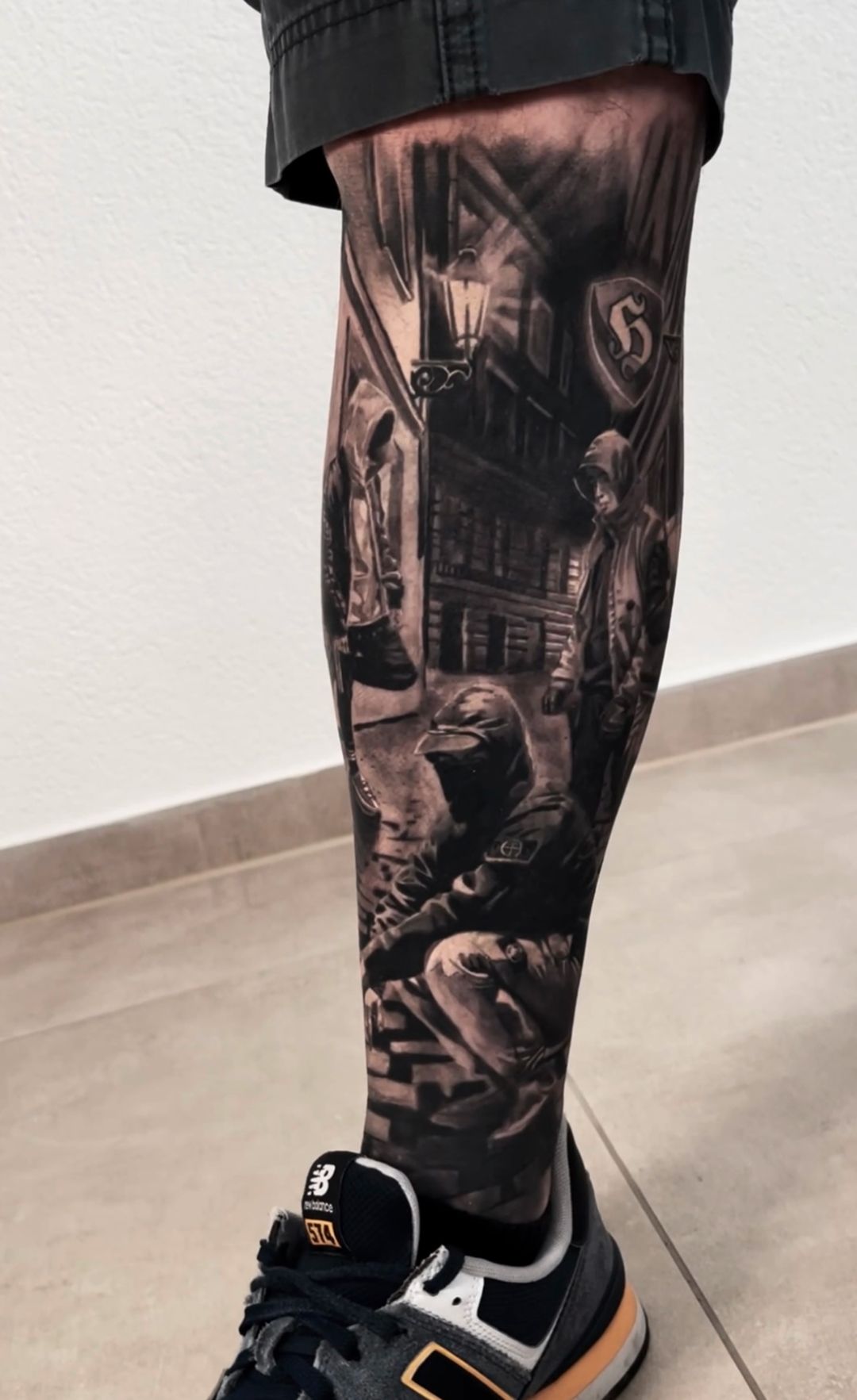 A person with a tattoo on their leg is wearing new balance shoes.