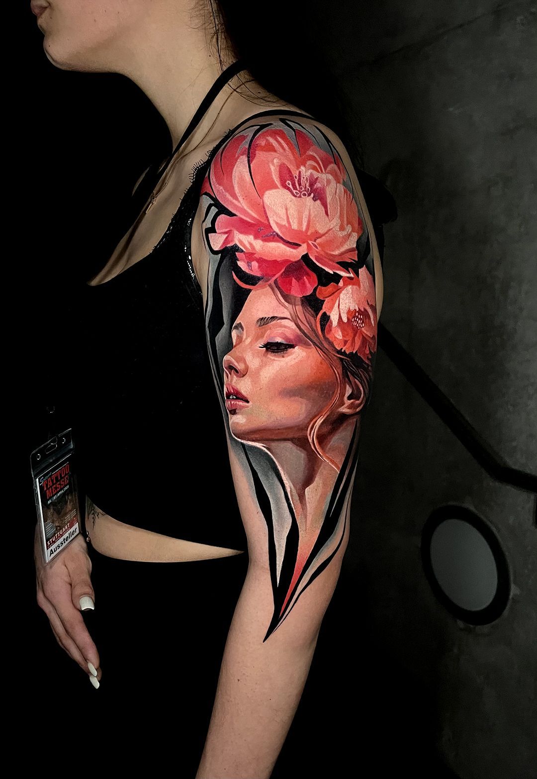 A woman has a tattoo of a woman 's face and flowers on her arm.