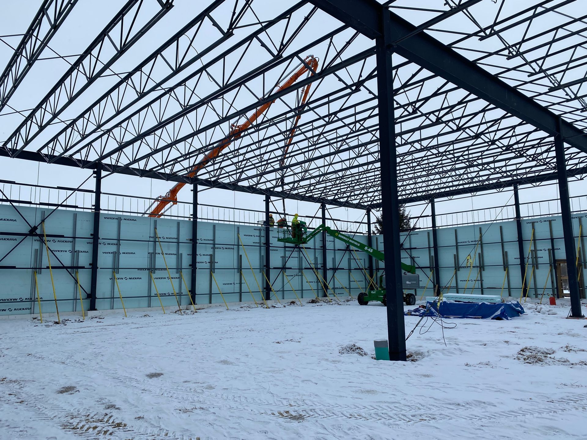 Snow-covered construction site with steel frame of a large building under construction