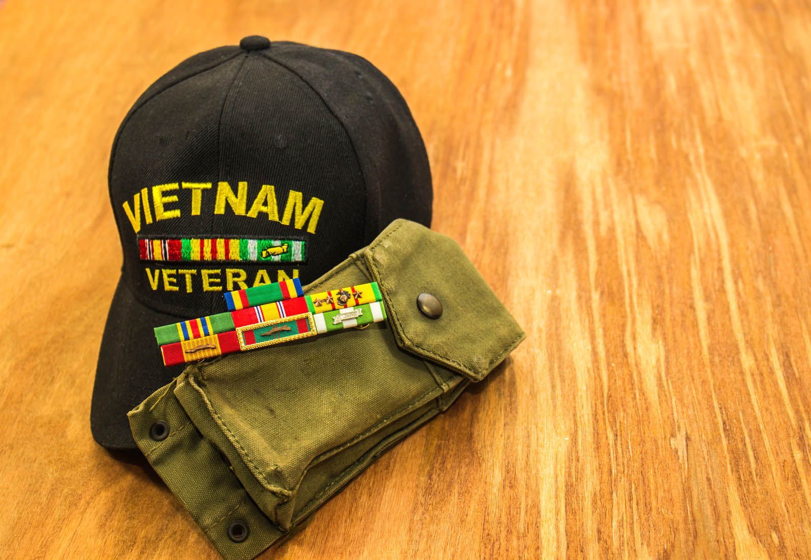 Vietnam Veteran cap with folded camouflage cloth on a wooden surface