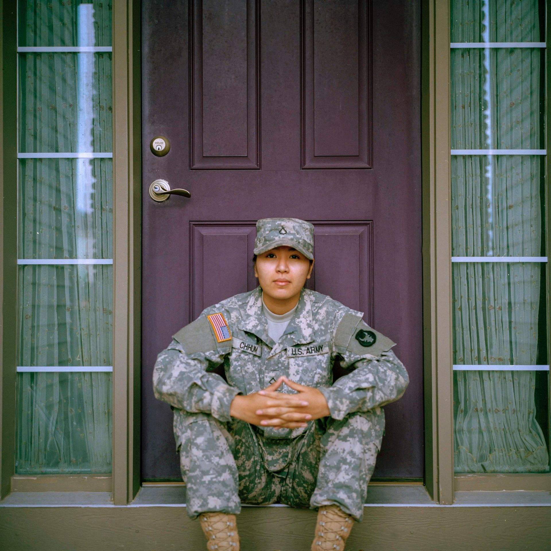 Soldier in camouflage uniform sitting on front steps in front of a purple door