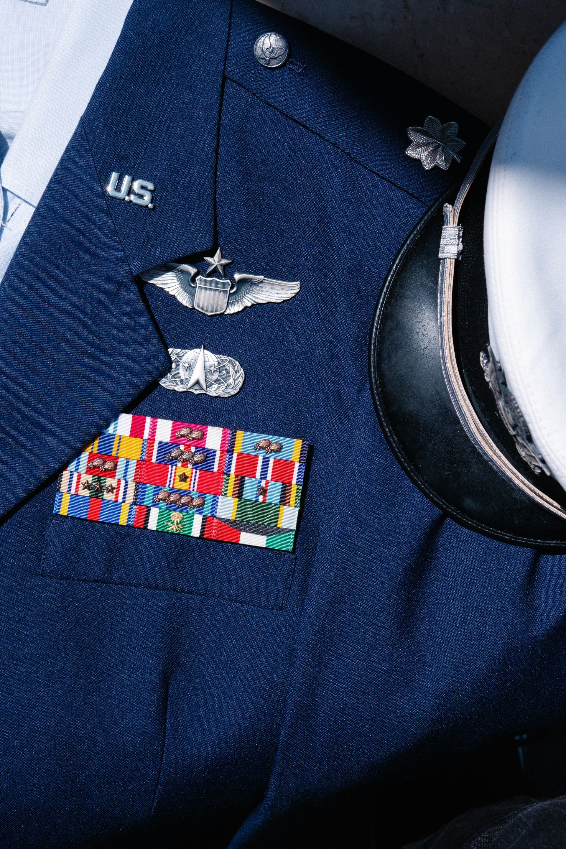 Close-up of a navy military uniform jacket with ribbons and insignia.