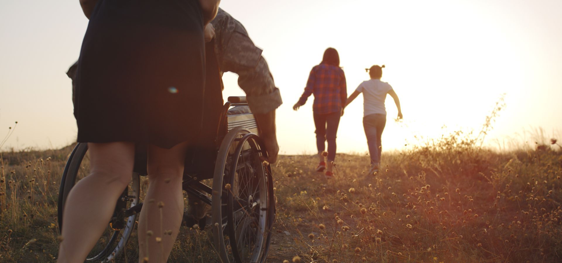 People walking and biking on a sunlit dirt path at sunset