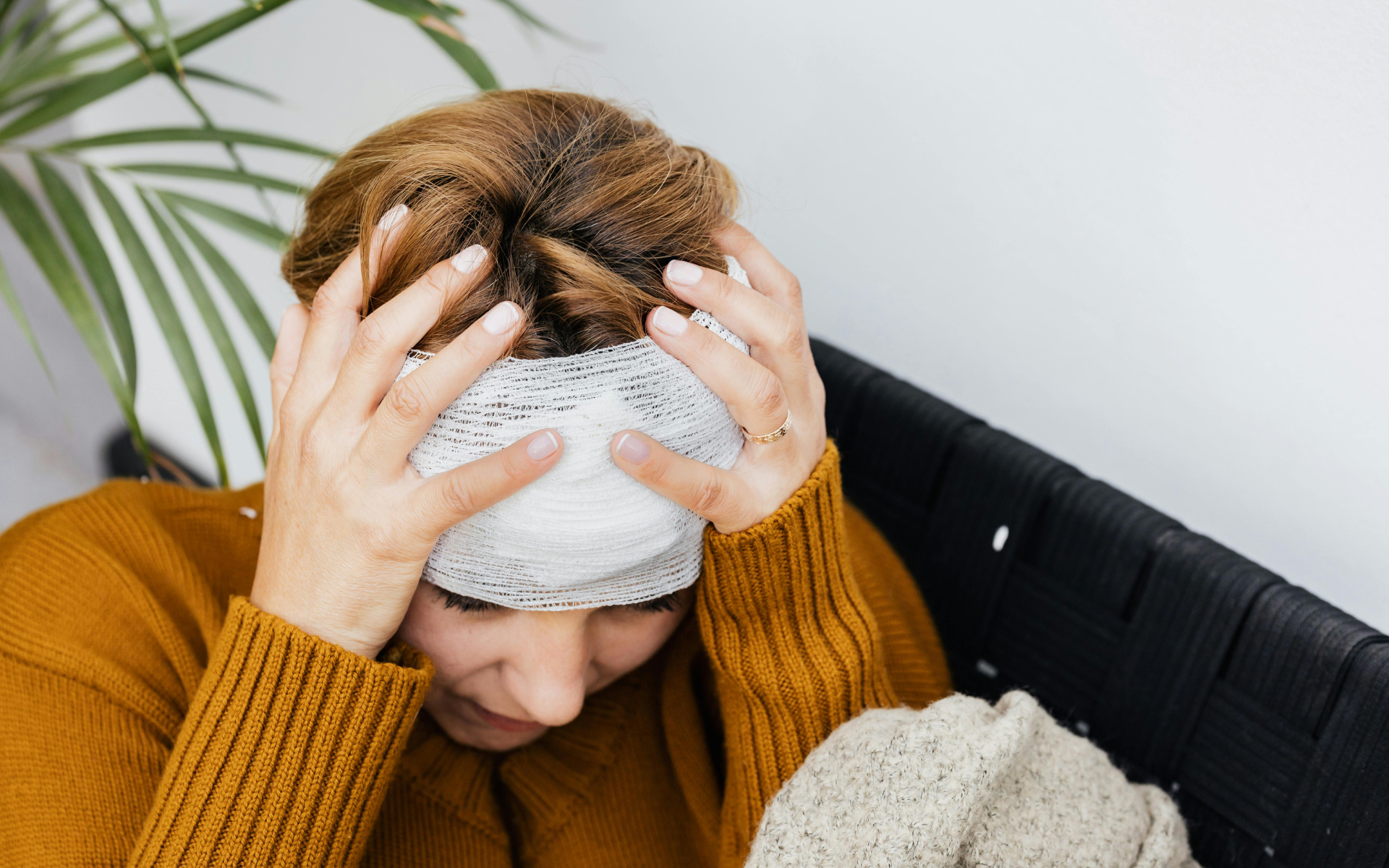 Person holding a towel to their head on a couch, looking unwell or stressed