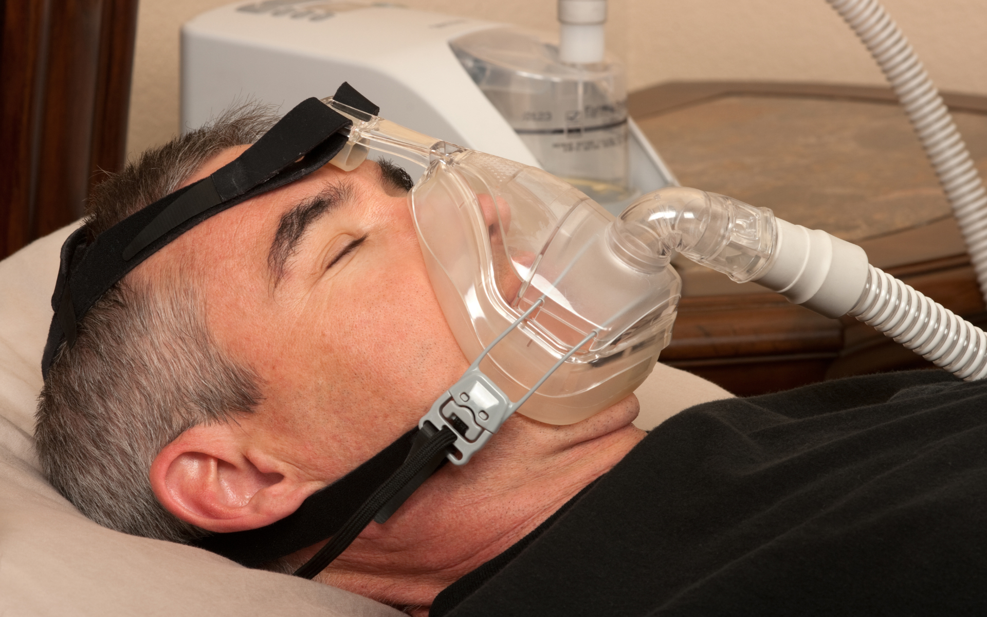 Man lying down wearing a clear oxygen mask connected to a machine