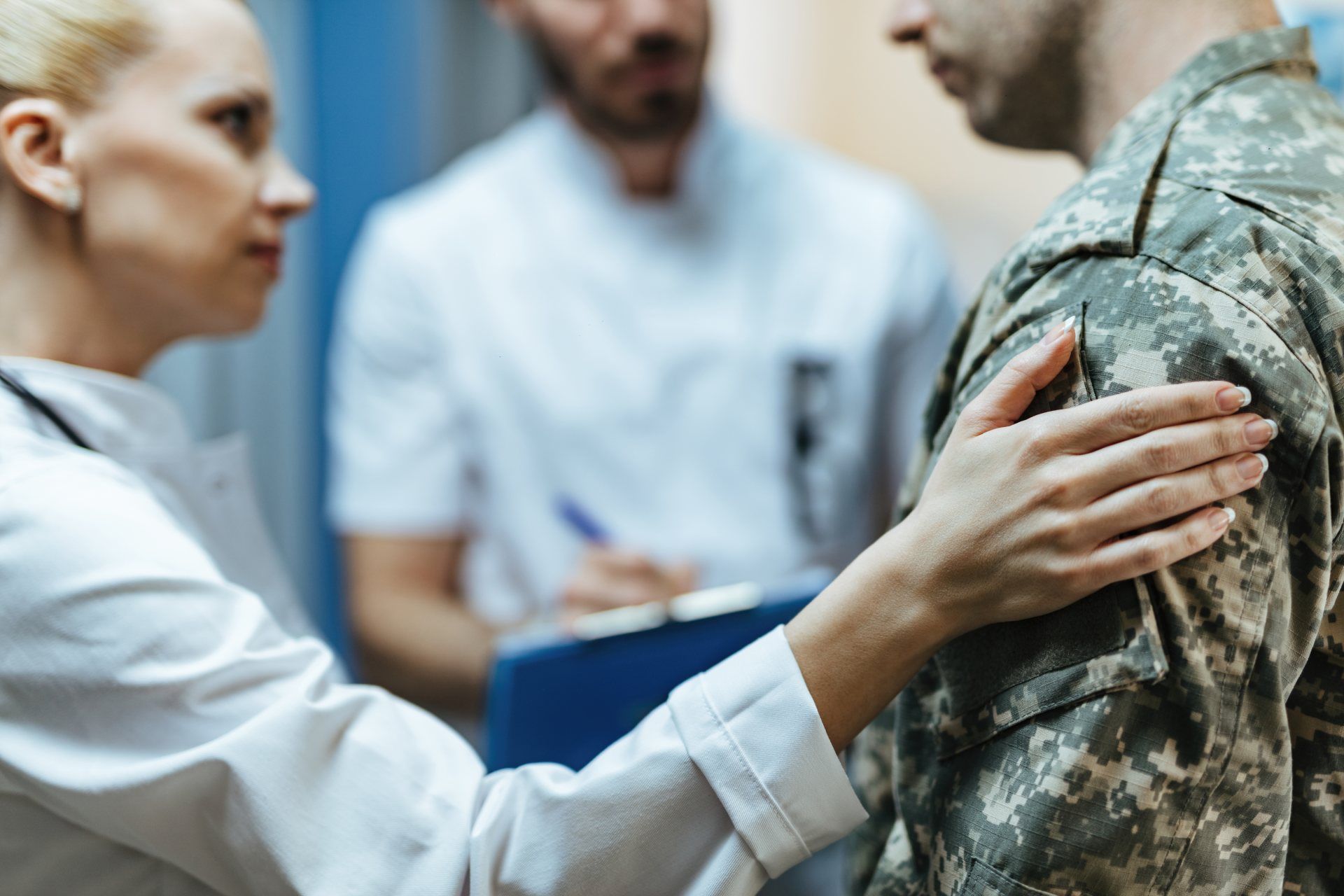 Doctor speaking with soldier, hand on shoulder, in clinic setting
