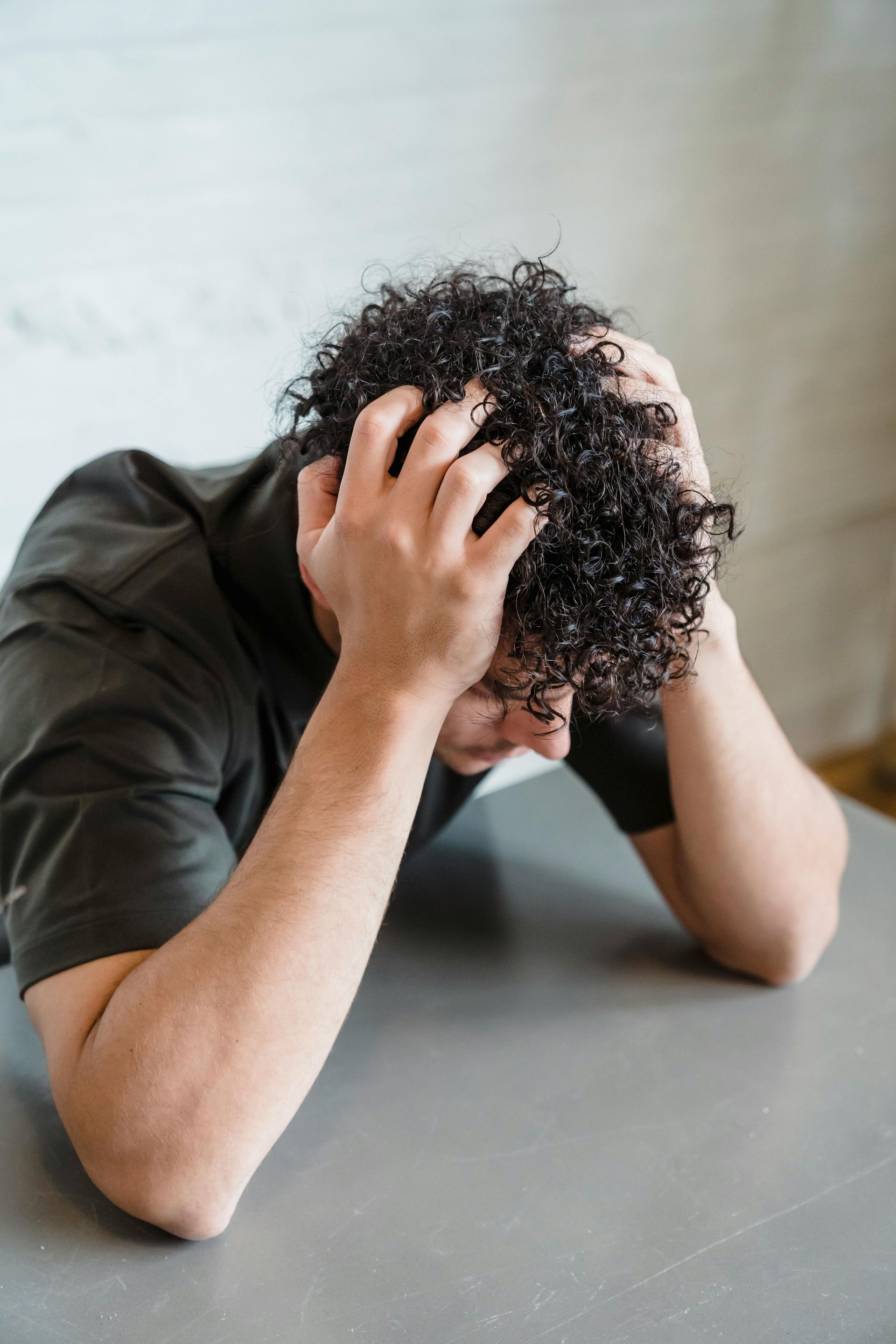 Person with head in hands at a table, appearing stressed or overwhelmed.