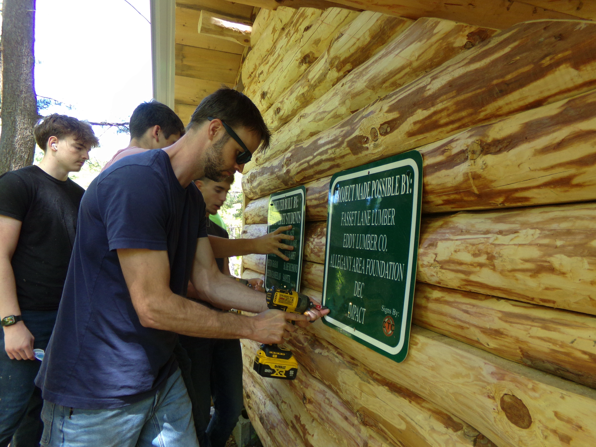 People installing a sign dedicated to community supporters on the lean-to.