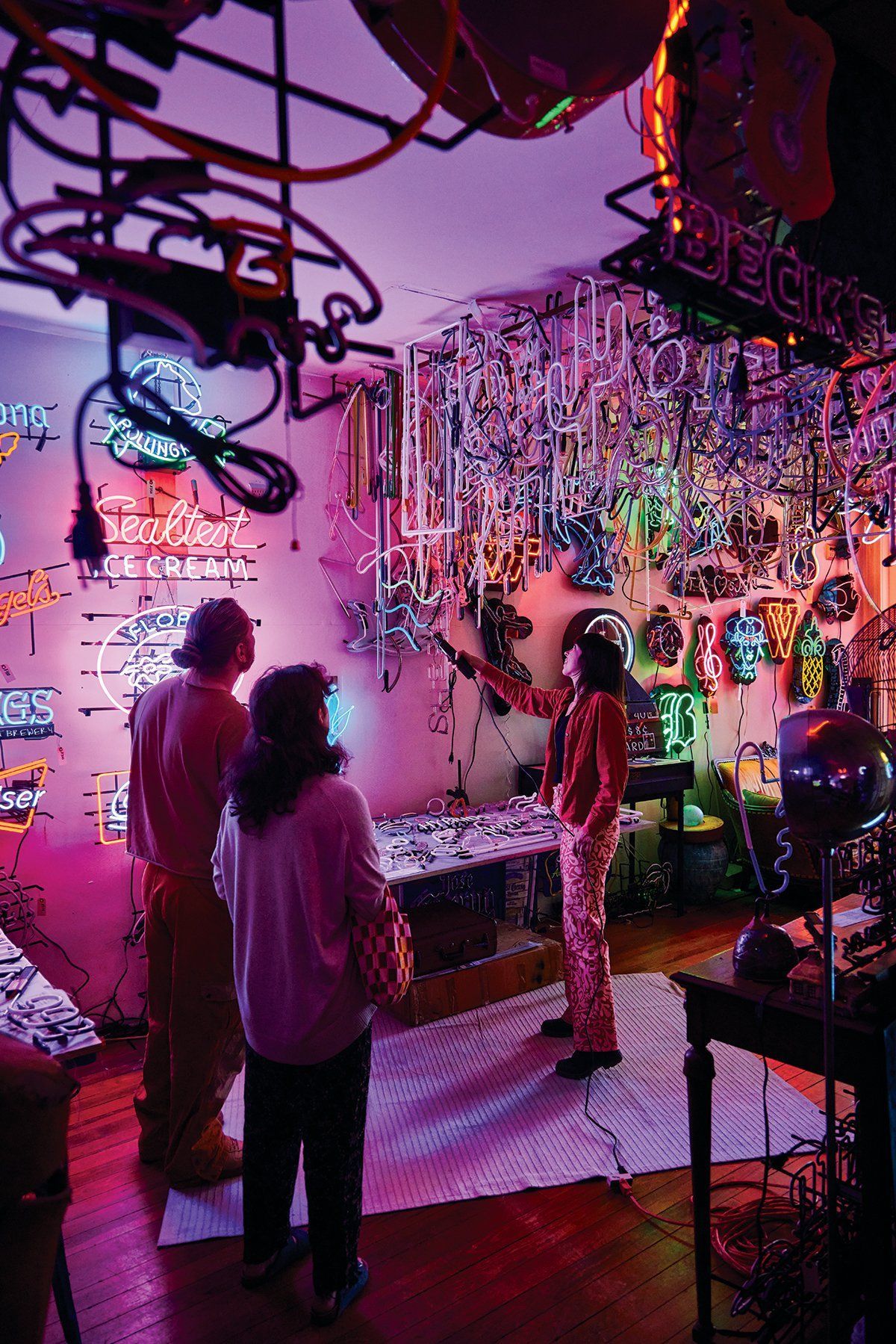 Chloe showing customers art in Uptown Neon, surrounded by glowing neon art.