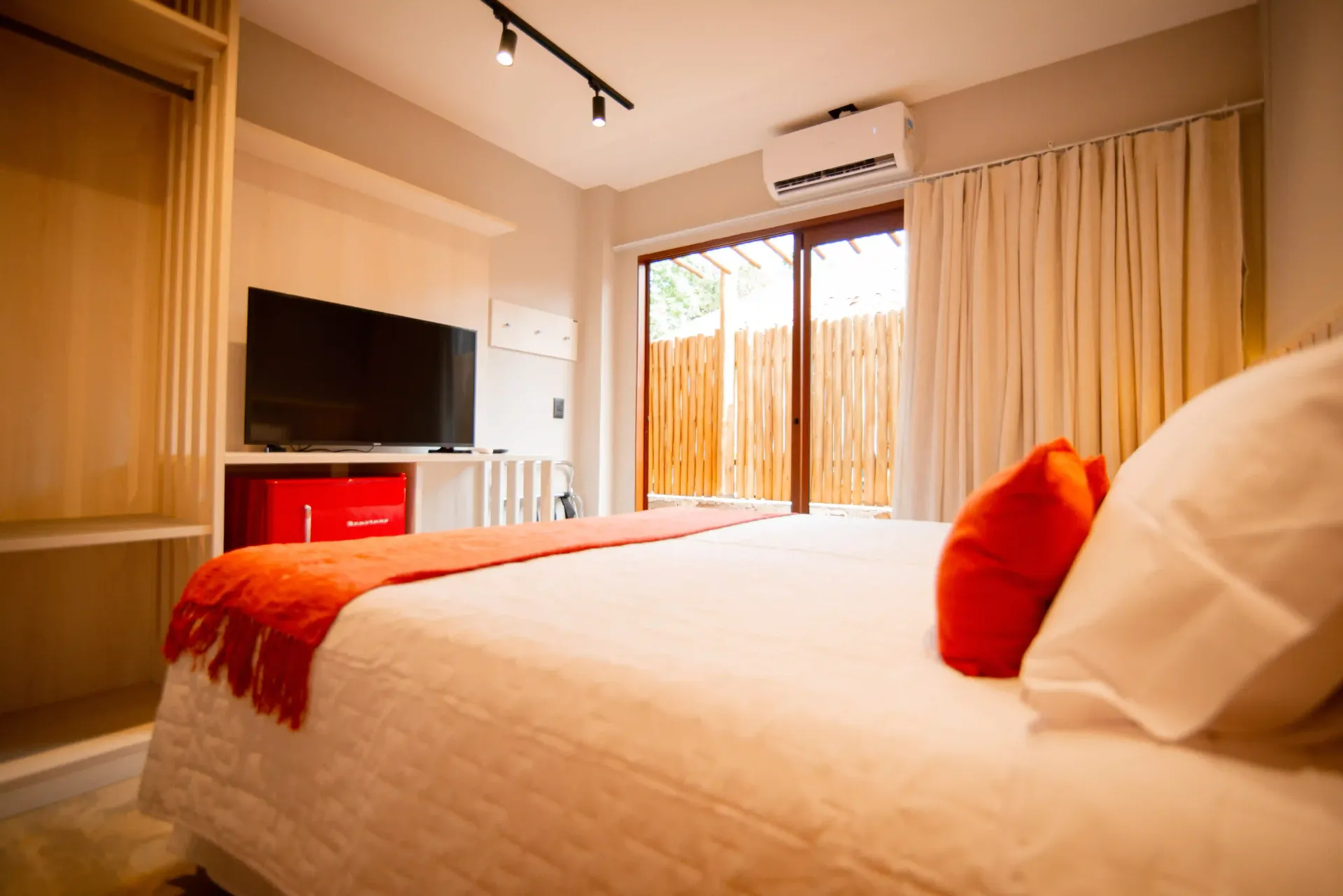 Um quarto com uma cama king size, televisão e portas de vidro deslizantes Pousada Xica