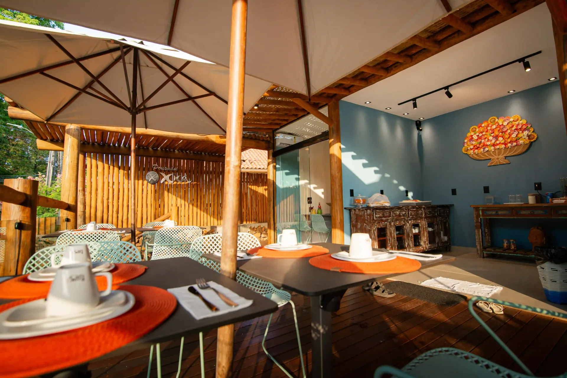 Um restaurante com mesas e cadeiras sob um guarda-sol Pousada Xica