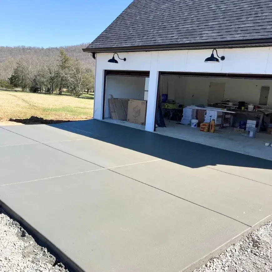 A garage with a concrete driveway in front of it