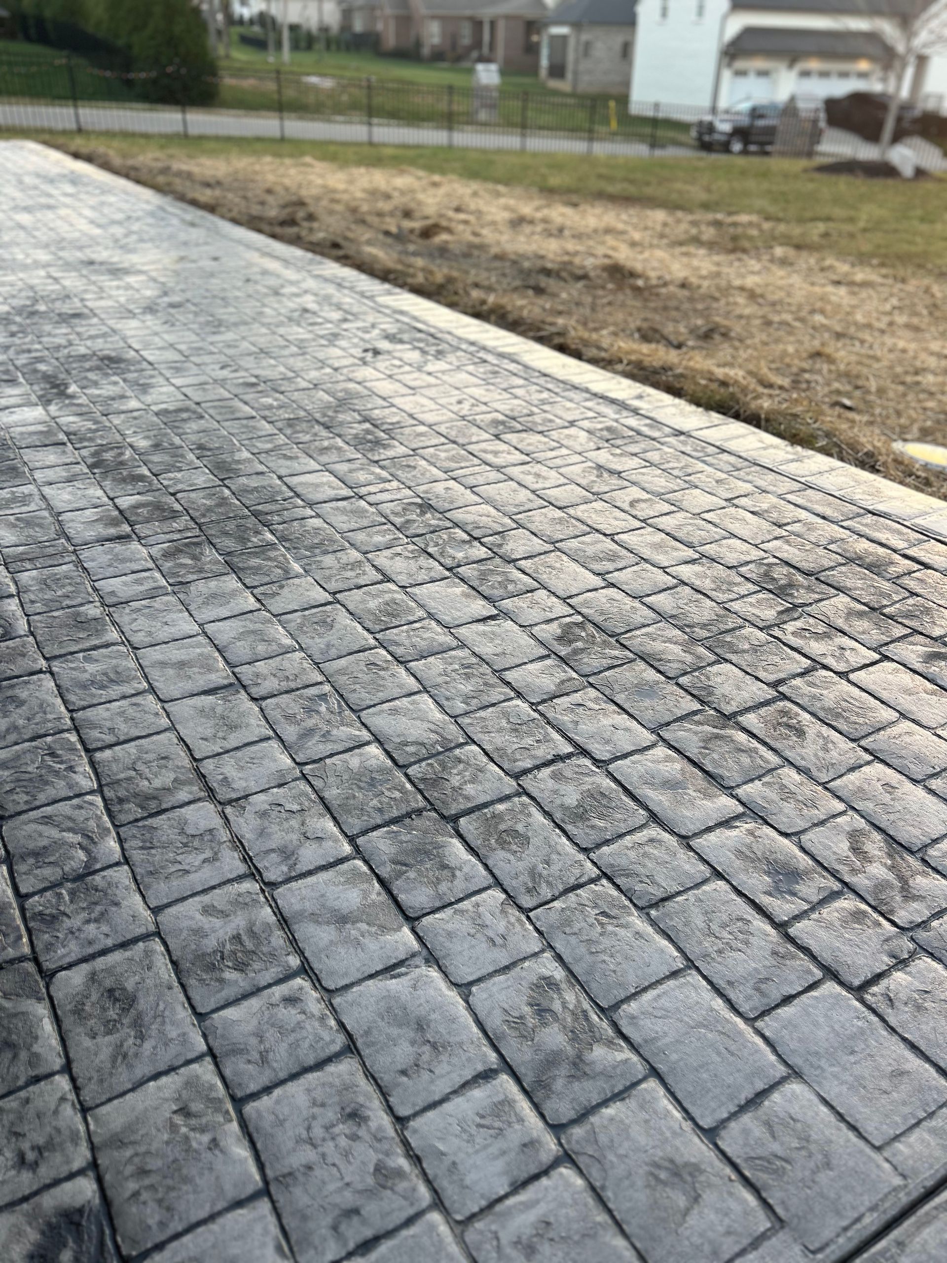 A brick walkway leading to a house in a residential area.