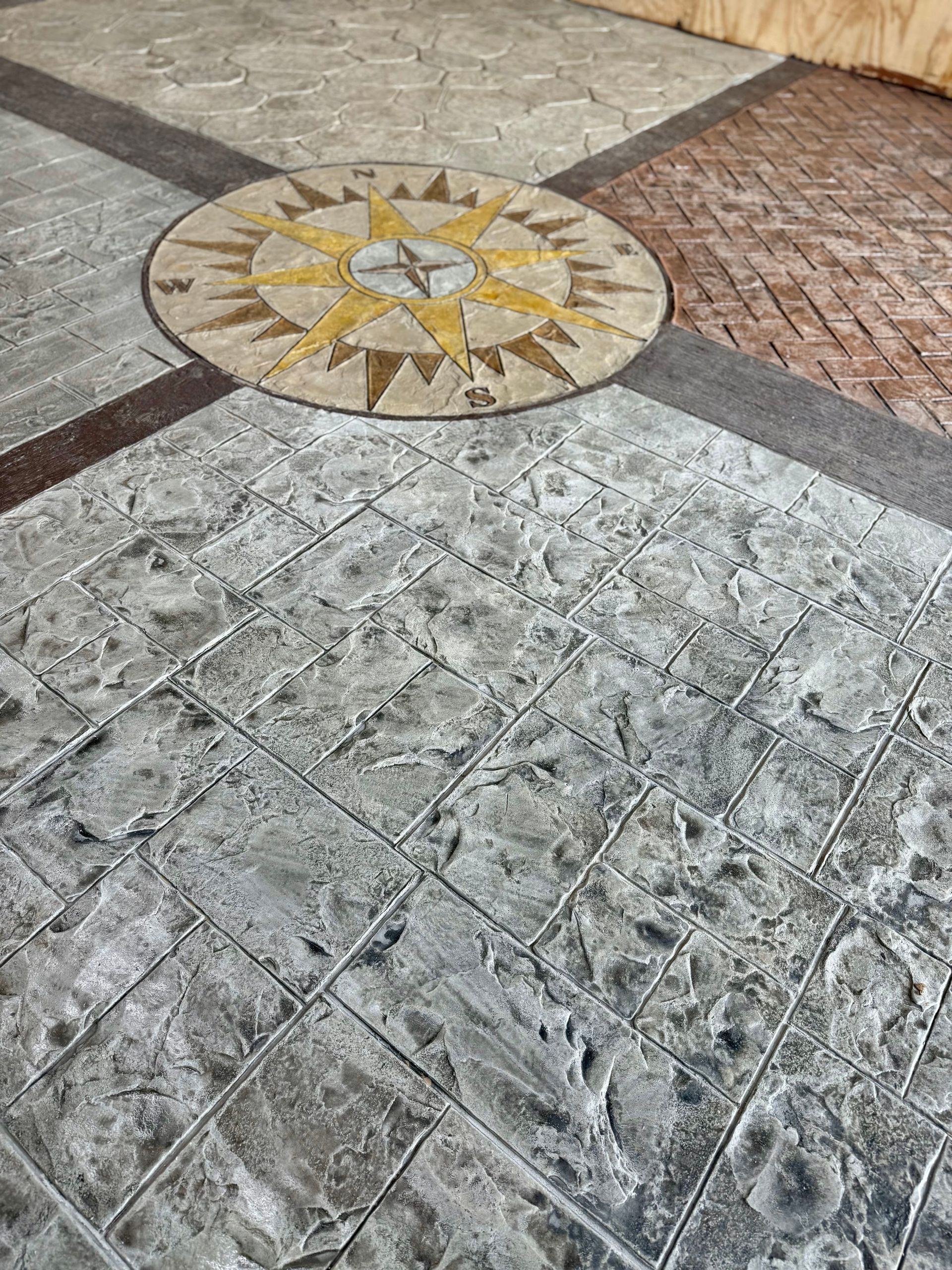 Stone walkway with a circular compass-like mosaic in yellow and white tiles