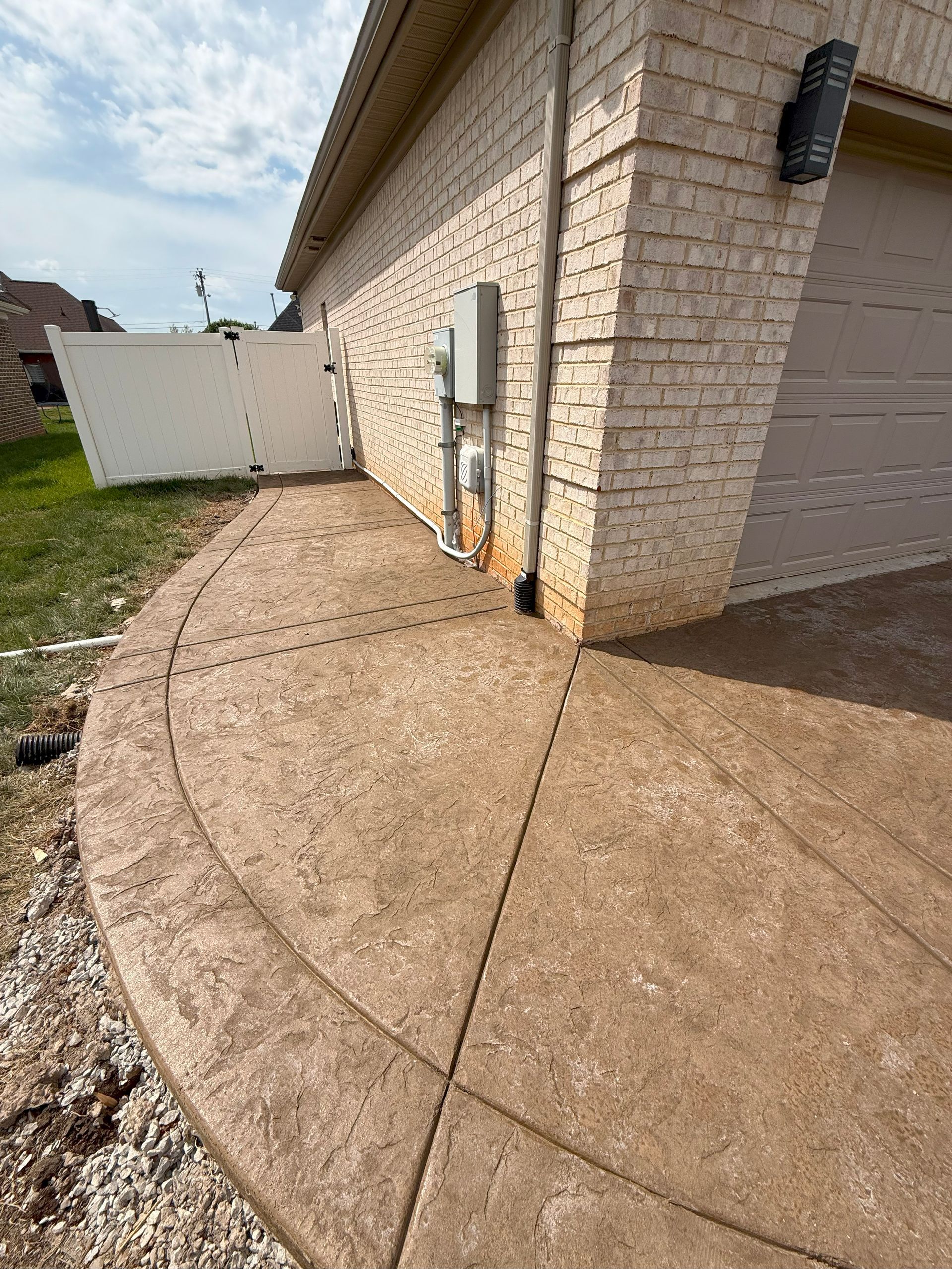 A brick house with a concrete walkway leading to it.