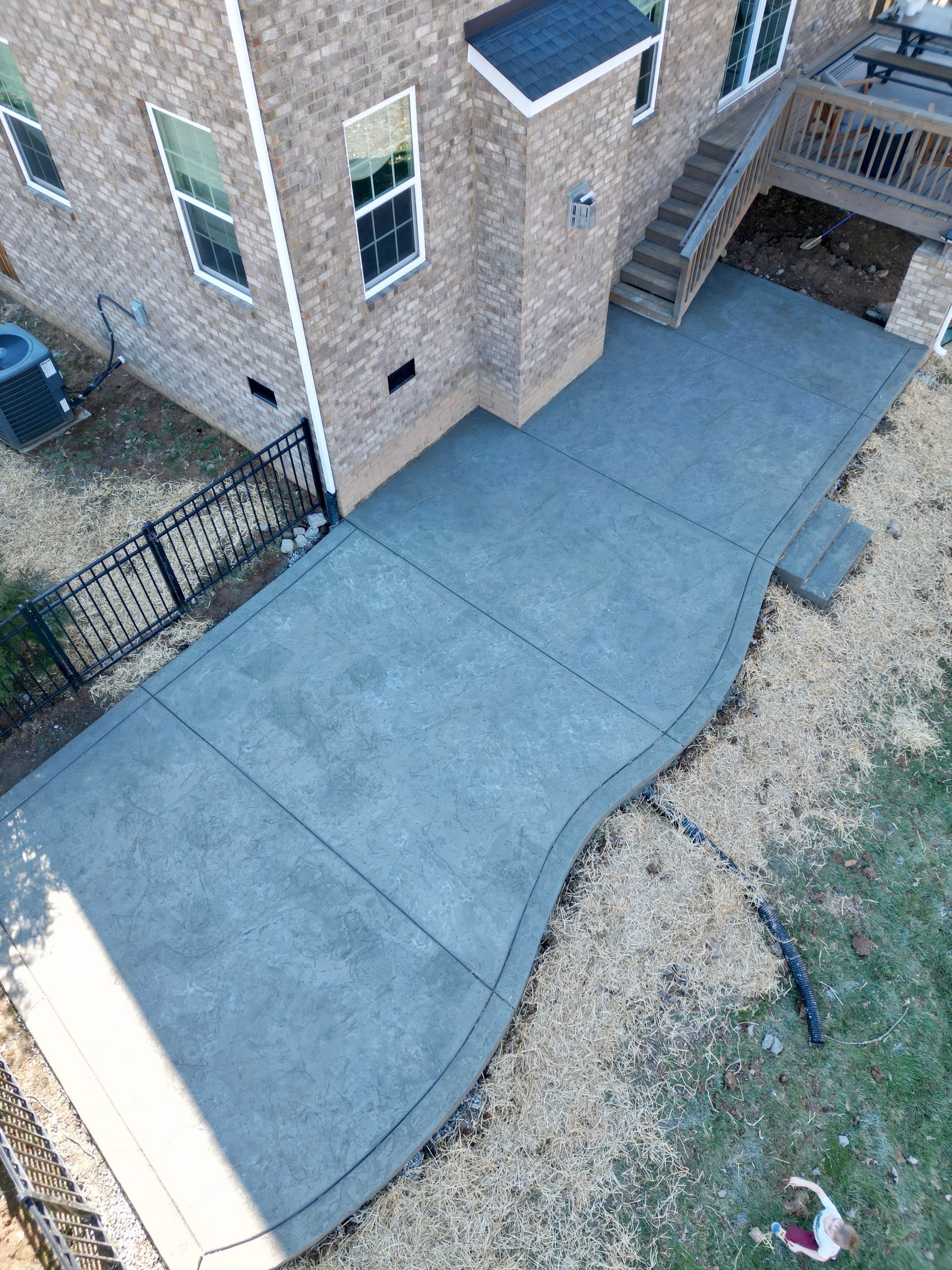 An aerial view of a concrete patio in front of a brick house.