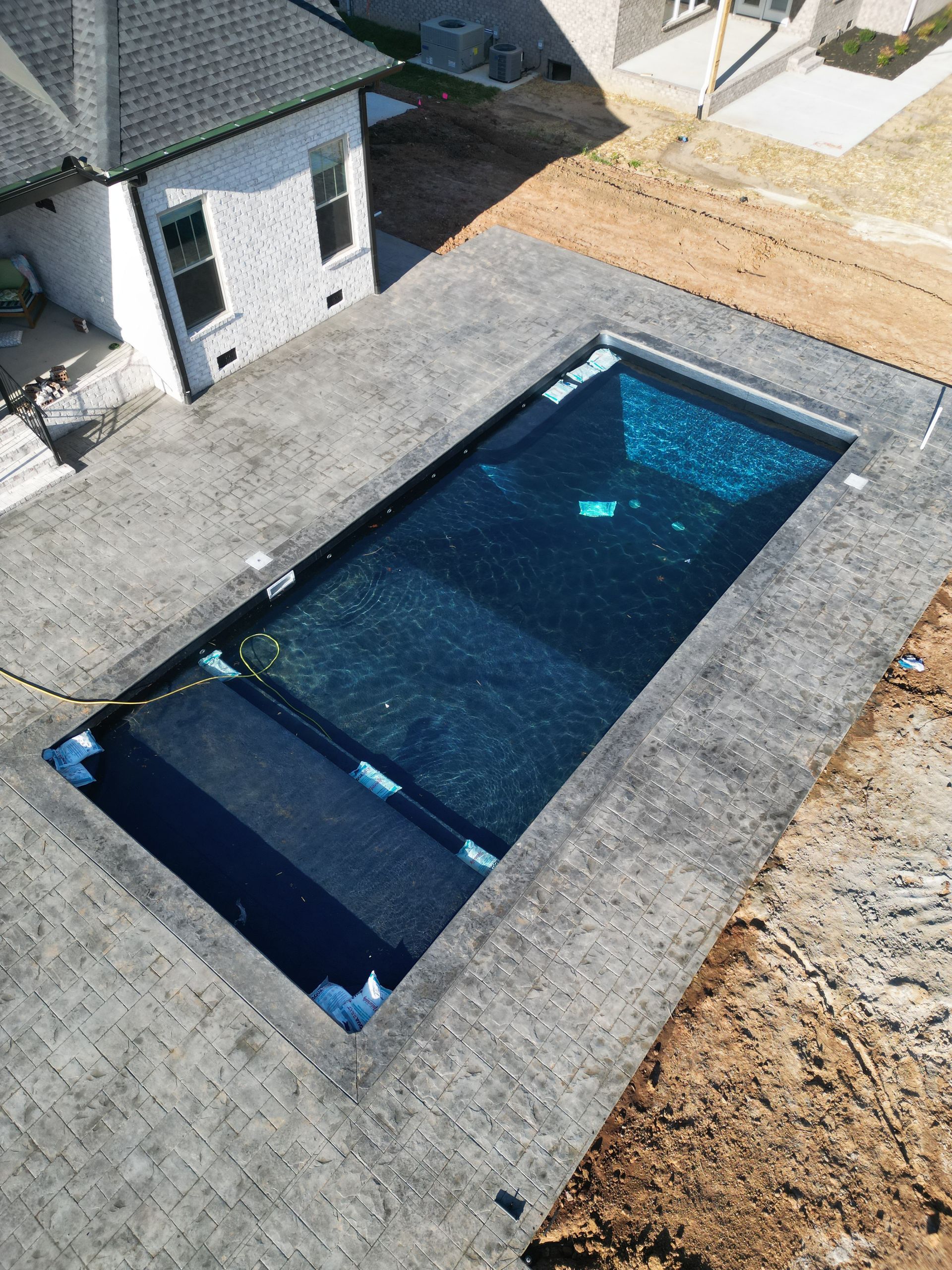 An aerial view of a large swimming pool in front of a house.