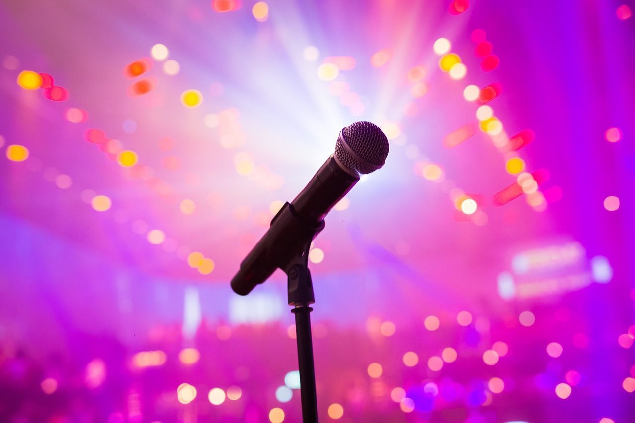 Microphone on stand with vibrant stage lights and blurred audience in the background