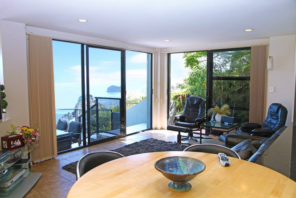 A living room with a table and chairs and a view of the ocean