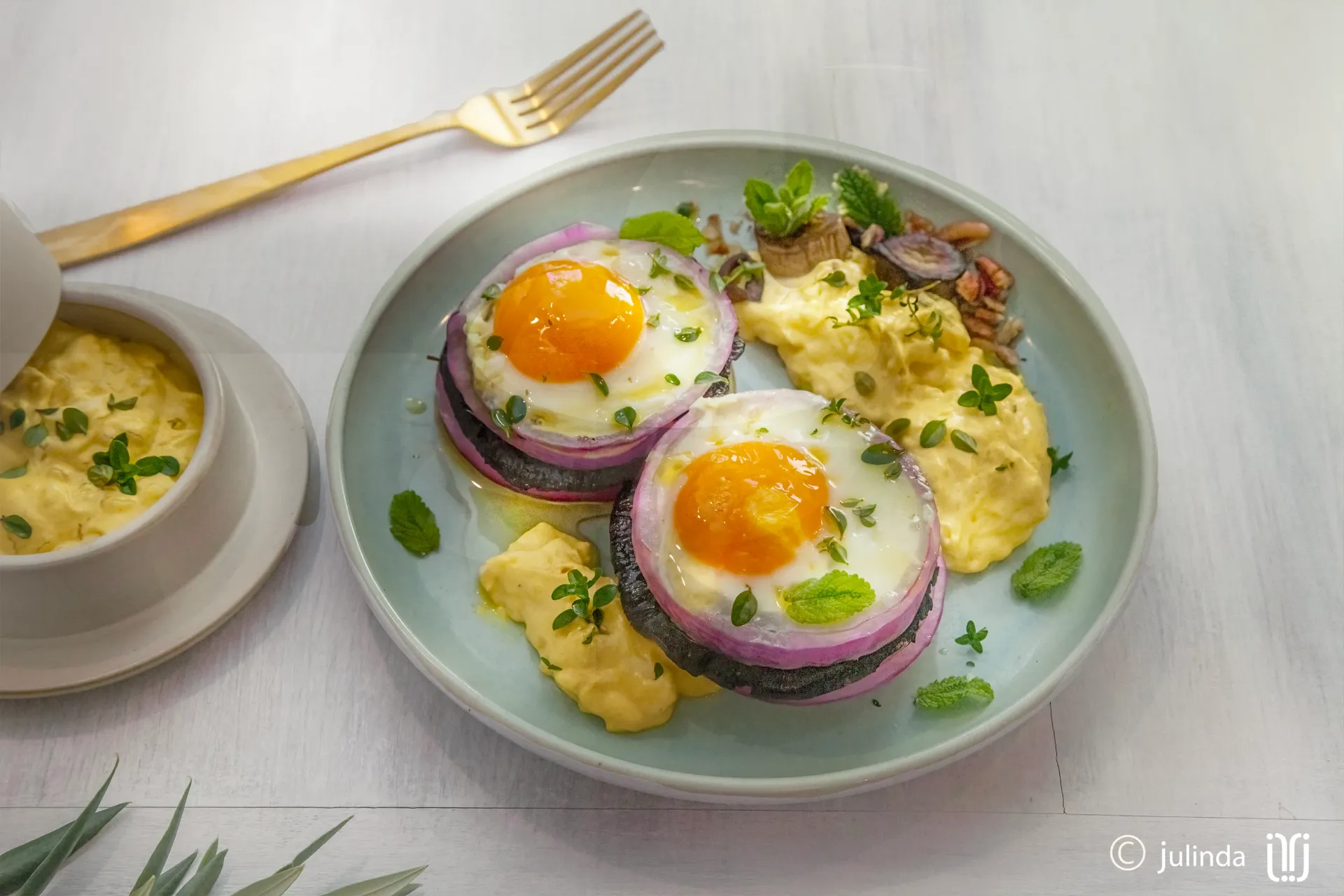 Overhead photography of a plate of organic chicken garnished with orange slices and red onion, with mint sprigs, a cinnamon stick, and a purple onion scattered around. Auckland food photographer.