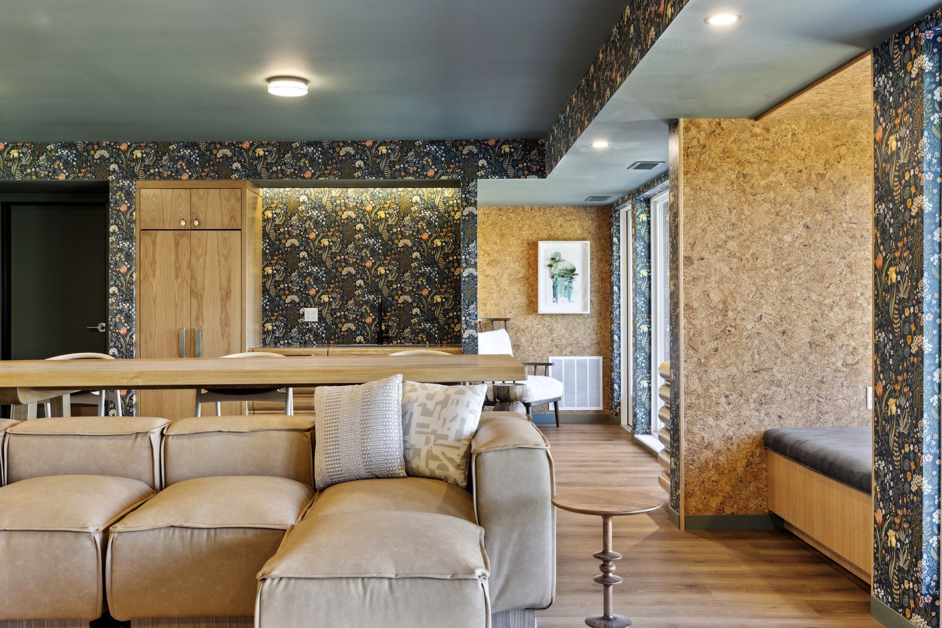 Lounge area with a tan sectional sofa, light wood floors, and walls with black and gold patterned accents.