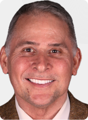 Man smiling, wearing a brown jacket, showing white teeth, against a light background.